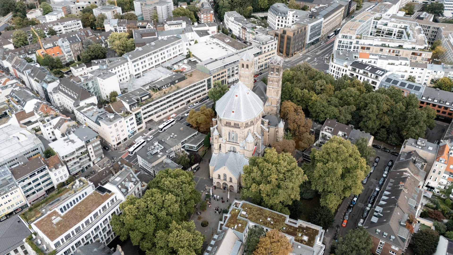 Luftaufnahme einer Stadt mit einer großen Kirche im Zentrum, umgeben von Gebäuden und Bäumen.