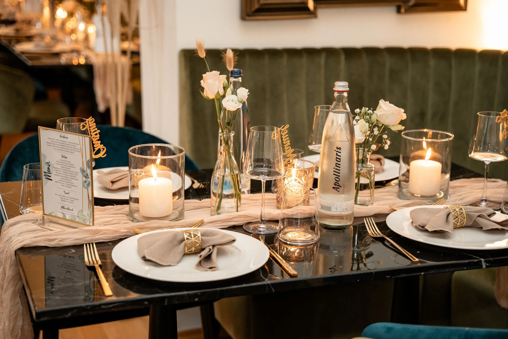 Festlich gedeckter Tisch mit Kerzen, Gläsern, Blumen und einer Menükarte