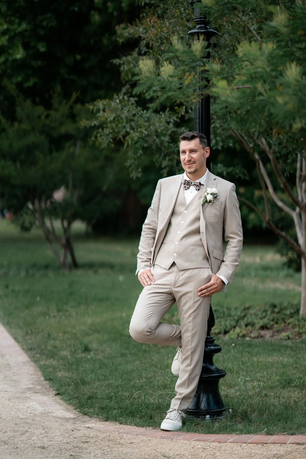 Junge Männer in Hochzeitsanzug, der an einem Laternenpfosten im Park steht.