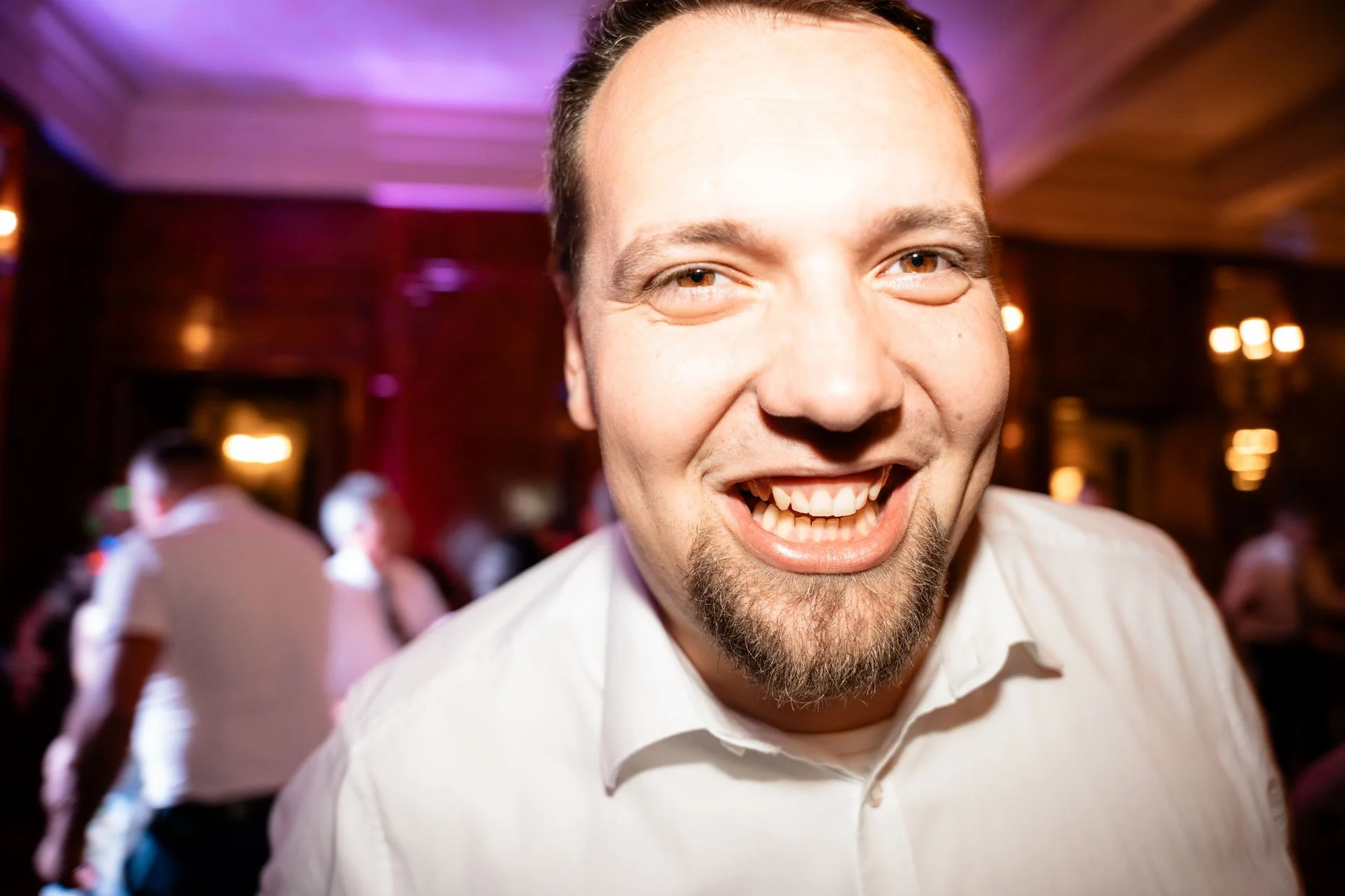 Lachender Mann in einem festlich dekorierten Raum mit Kirchenbank-Hintergrund.