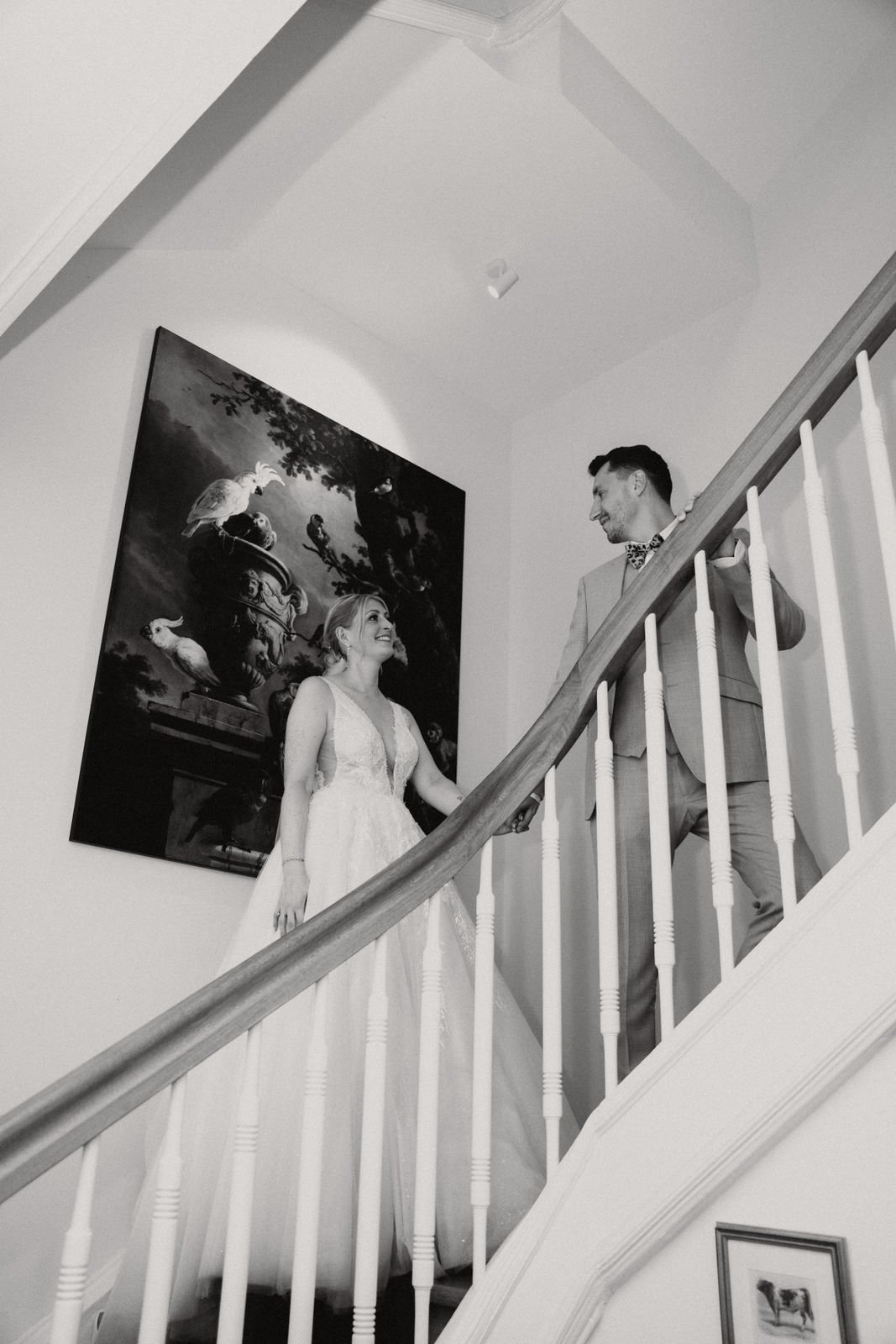 Braut und Bräutigam halten Händchen auf einer Treppe bei ihrer Hochzeit, schwarz-weiß Fotografie