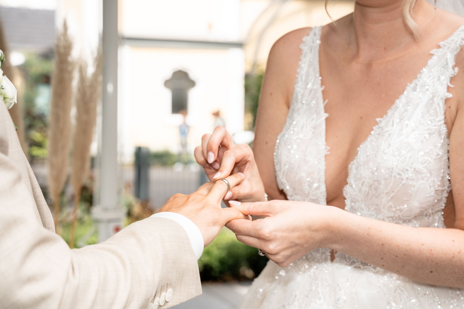 Eine Braut legt ihren Ehering an die Hand ihres Partners während einer Hochzeitszeremonie.