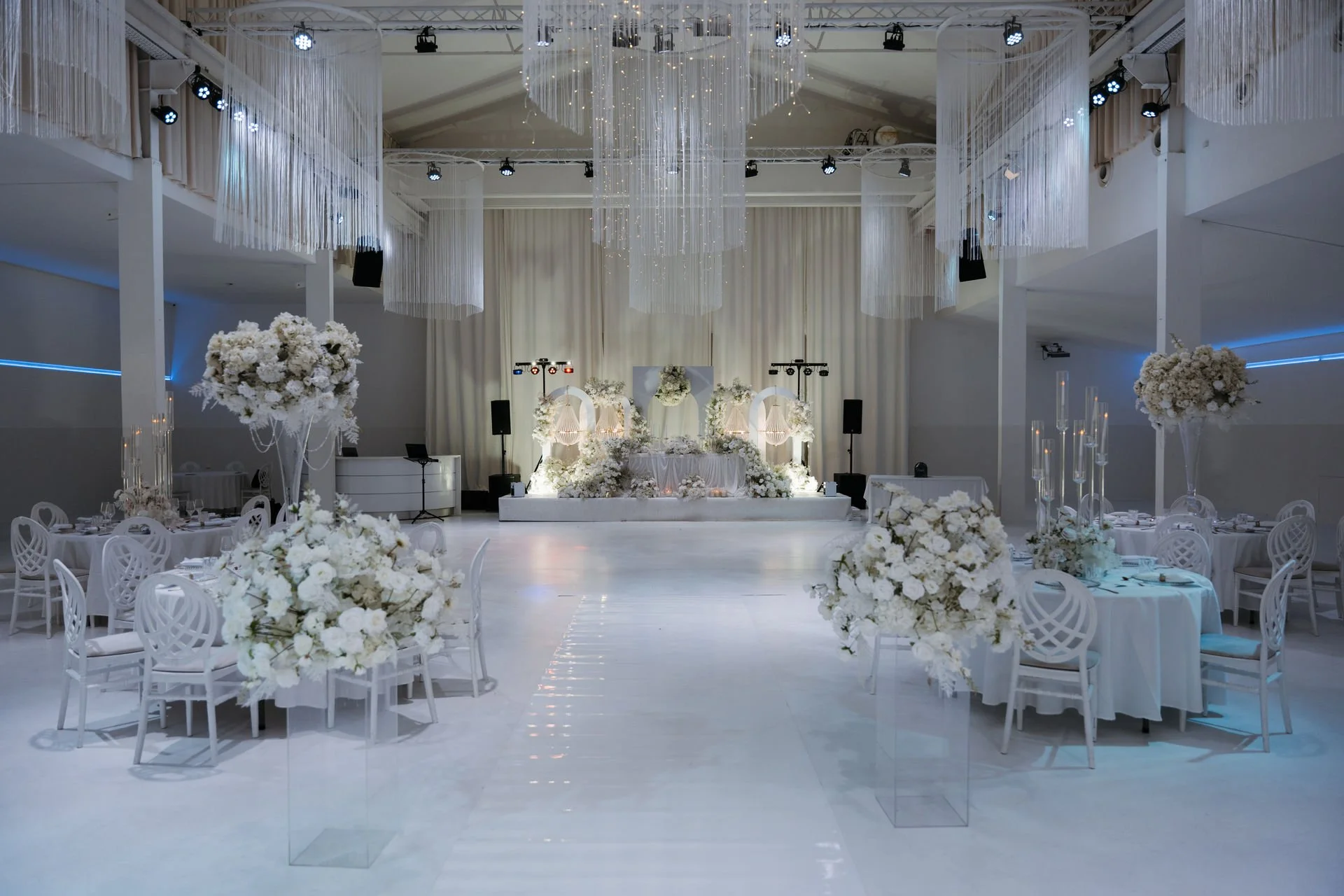 Weiße Hochzeitslocation mit Blumenarrangements und Tanzfläche