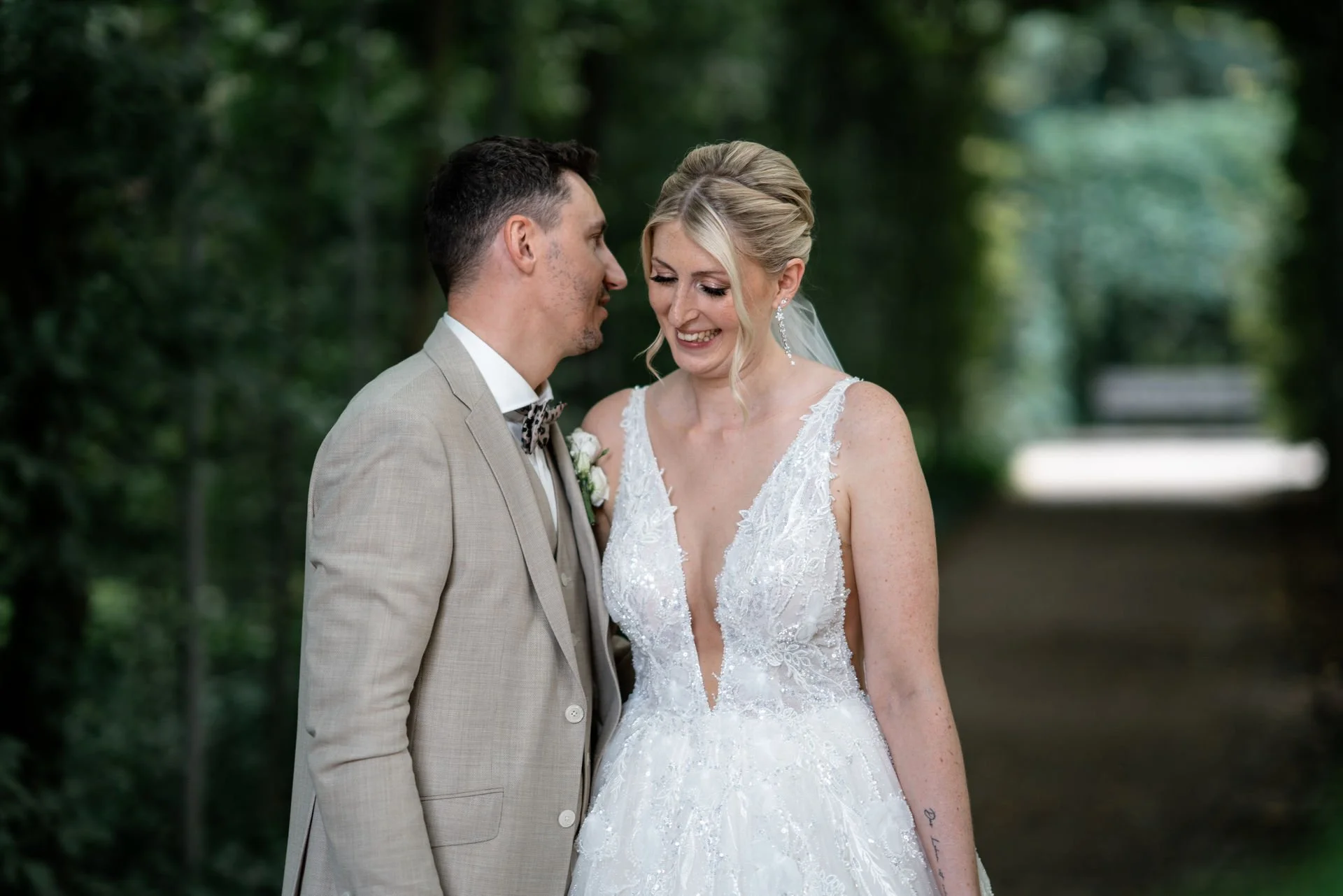 Braut und Bräutigam stehen sich im Grünen, lachen und schauen sich verliebt an.