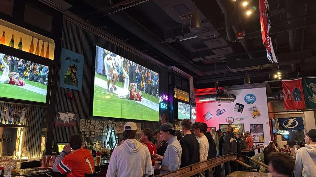 Packed night at Tampa Burgers and Pirates, group of friends watching football game on large screen