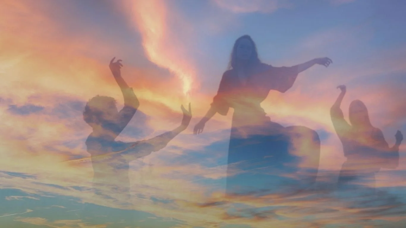 Silhouettes of three people in a dance pose against a colorful sky at sunset, with clouds and vibrant hues of orange, pink, and blue.