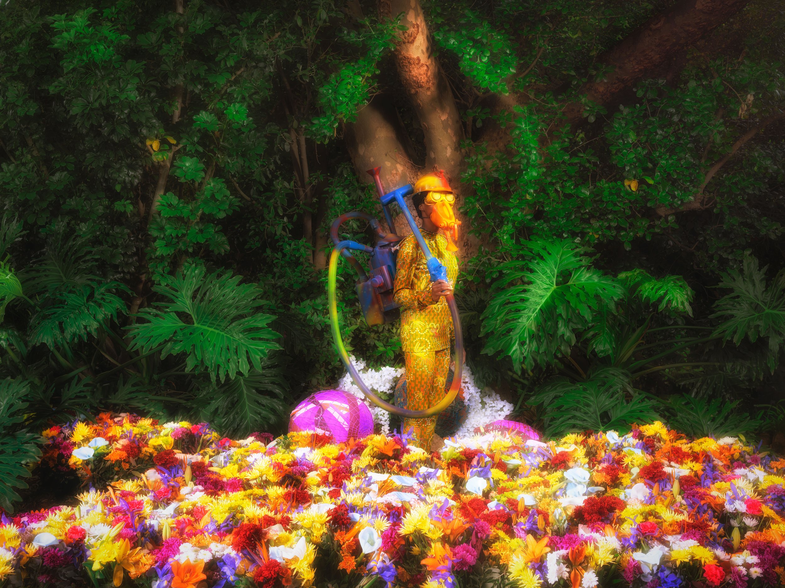 Person in colorful outfit with a gas mask standing in a vibrant garden with various flowers and green foliage.