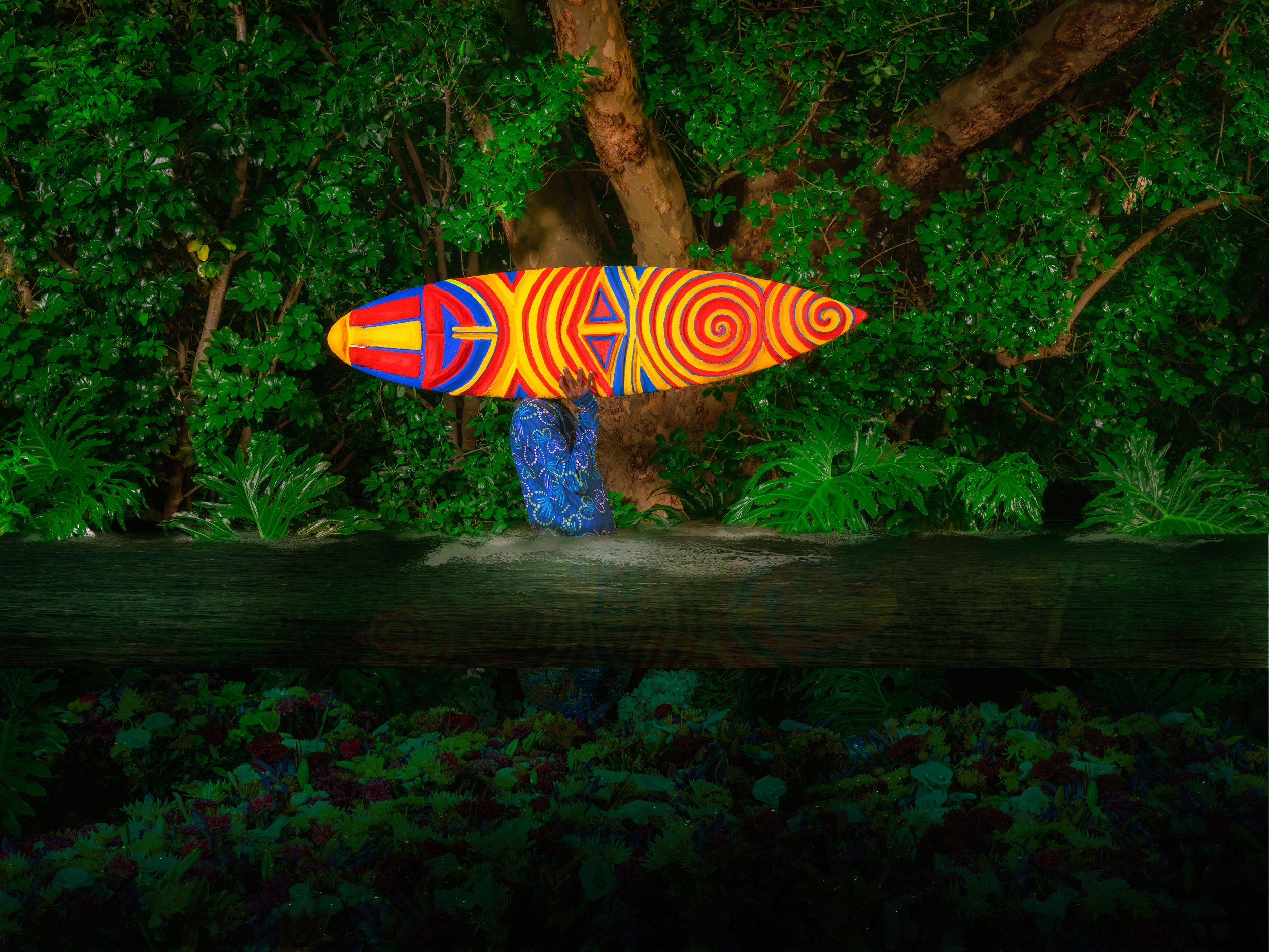 Colorful surfboard leaning against a tree in a lush green forest background.
