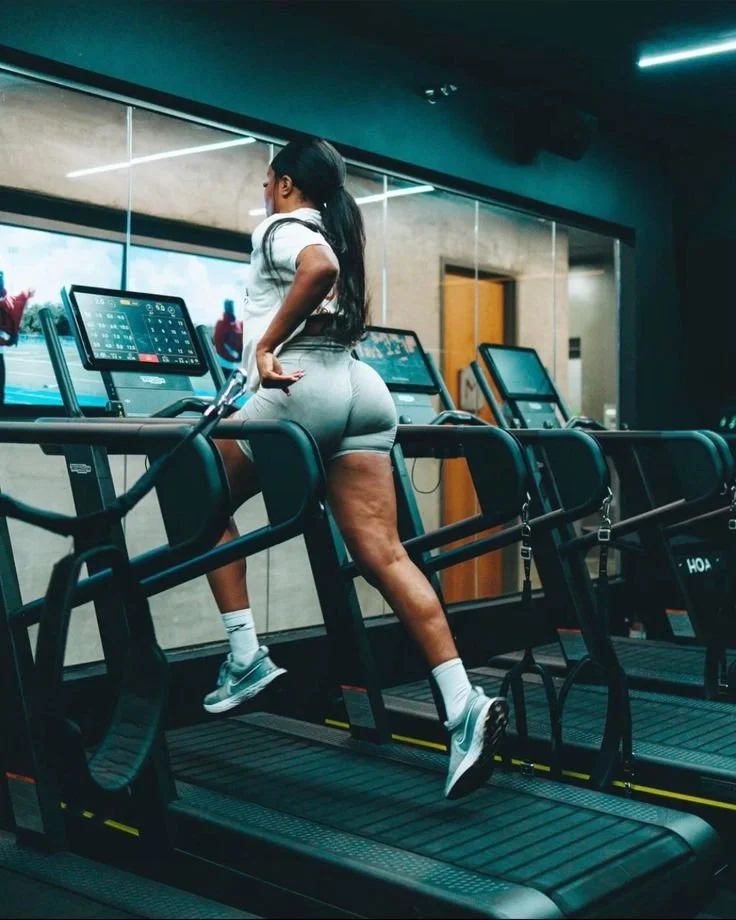 A woman in workout clothes running on a treadmill in a gym.