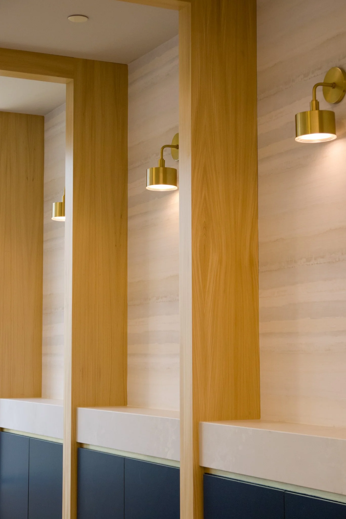 The hallway of a beautifully designed, contemporary commercial office space, featuring gold sconces and wooden paneling.