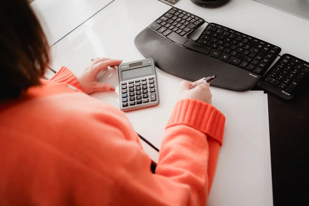 Image of back of Rachel whilst she works at her desk with calculator and pen in hand.