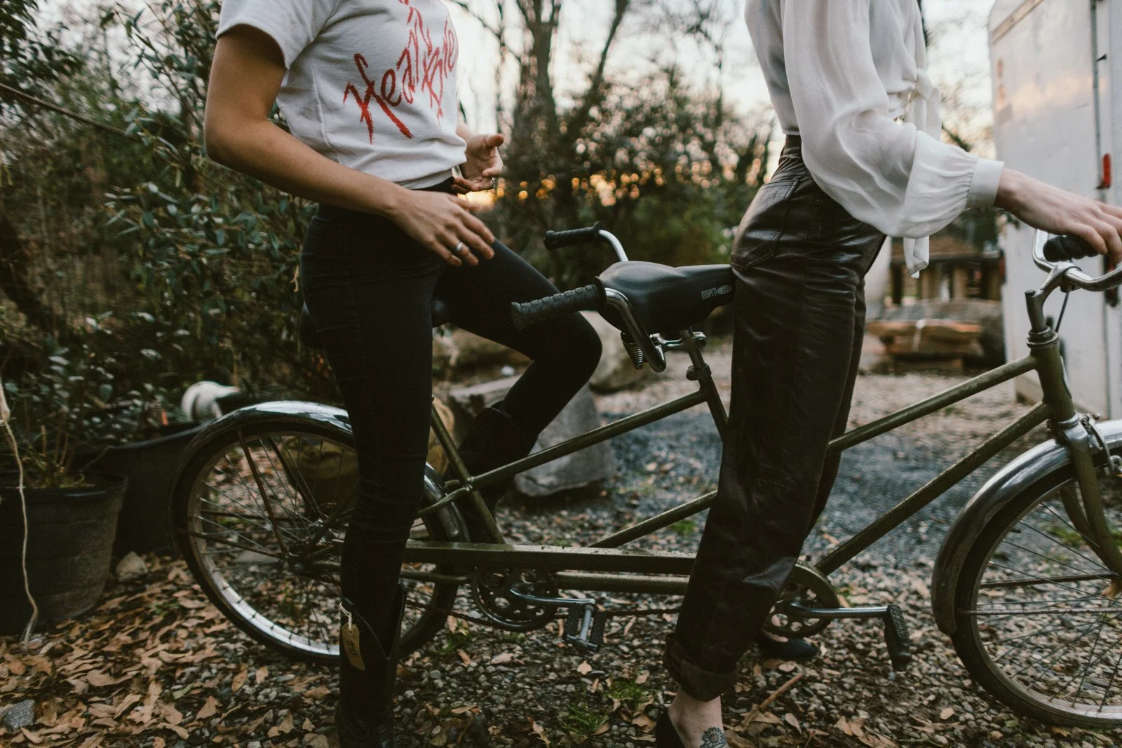 Two people standing with a vintage tandem bicycle outdoors.