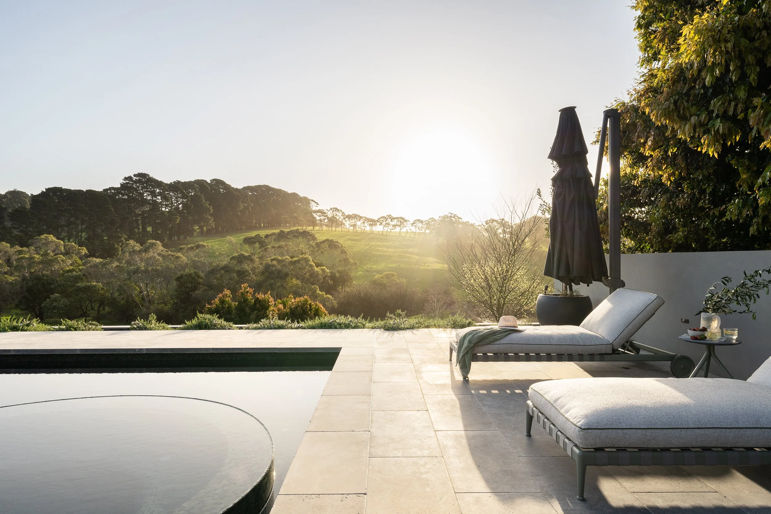 Image of Red Hill project by Mint Landscape Design showing the edge of the pool and spa with sun loungers overlooking rolling hills with trees