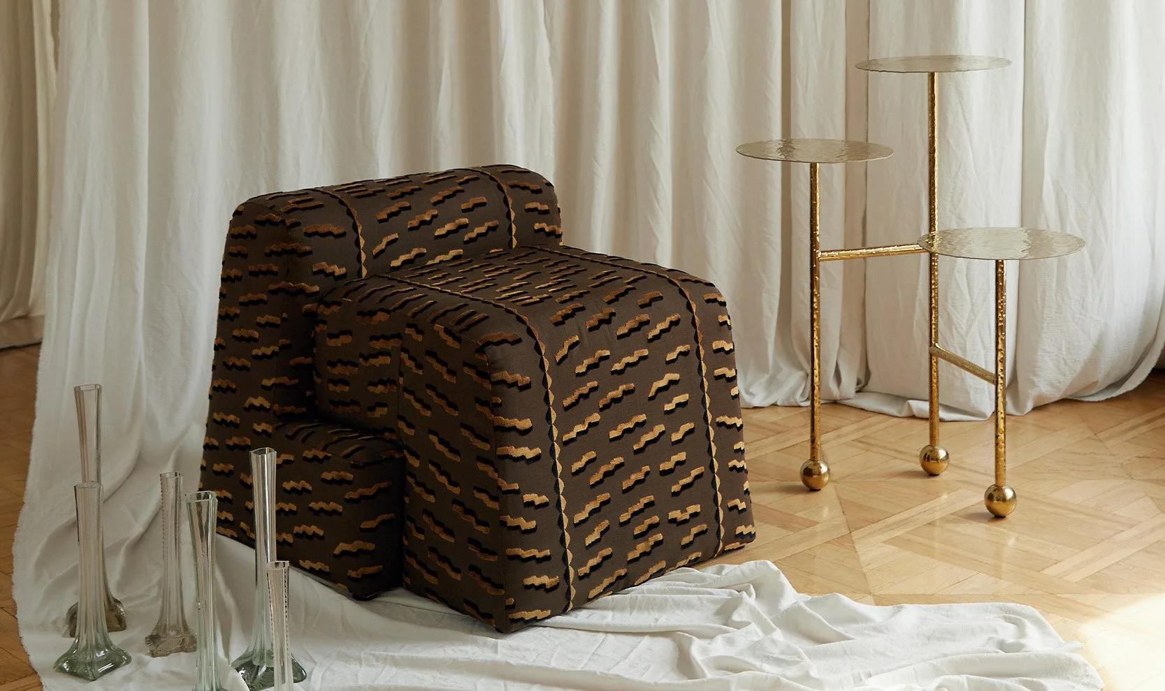 The sculptural Liquid Table Gold used as a side table next to the Valun Armchair by Furn Object in a contemporary living room