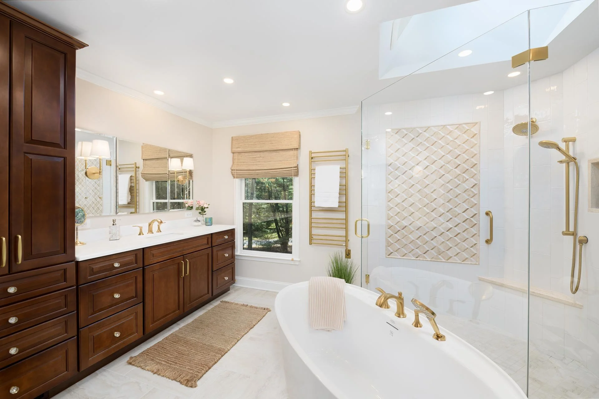 Luxury bathroom featuring a freestanding bathtub, glass-enclosed shower, wooden cabinets, gold fixtures, and large mirrors.