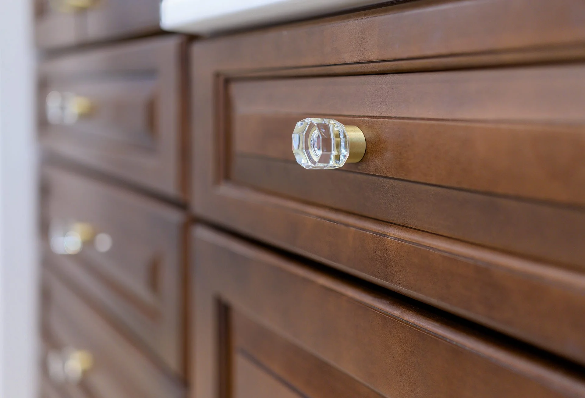 Close-up of wooden cabinet drawers with decorative crystal knobs.