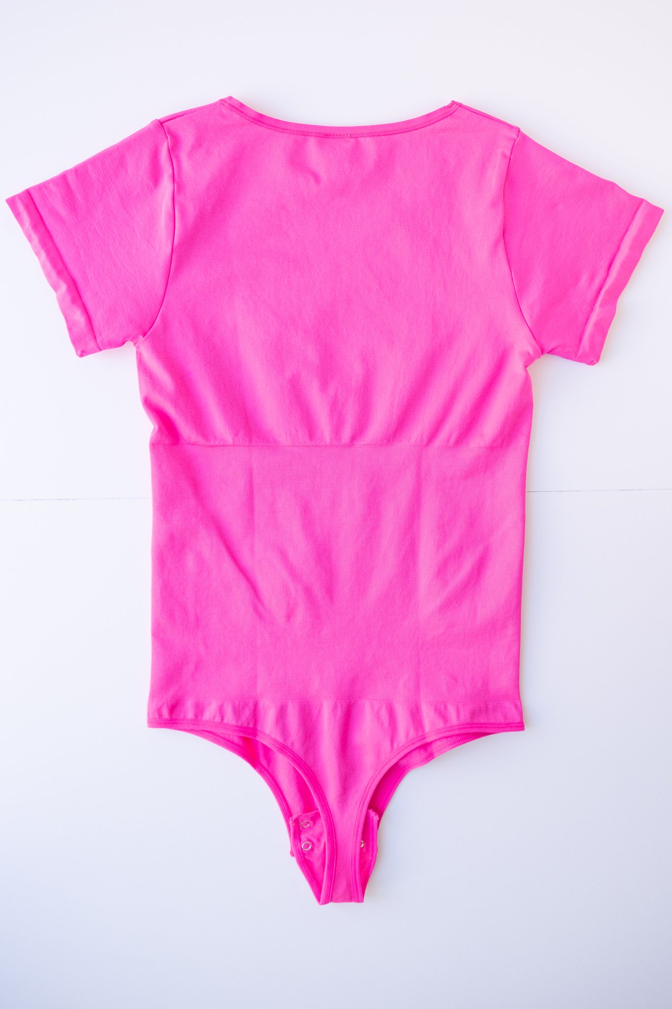 Vibrant pink short sleeve bodysuit with a contouring waist control feature. Designed with soft, elastic fabric for all-day wearability.