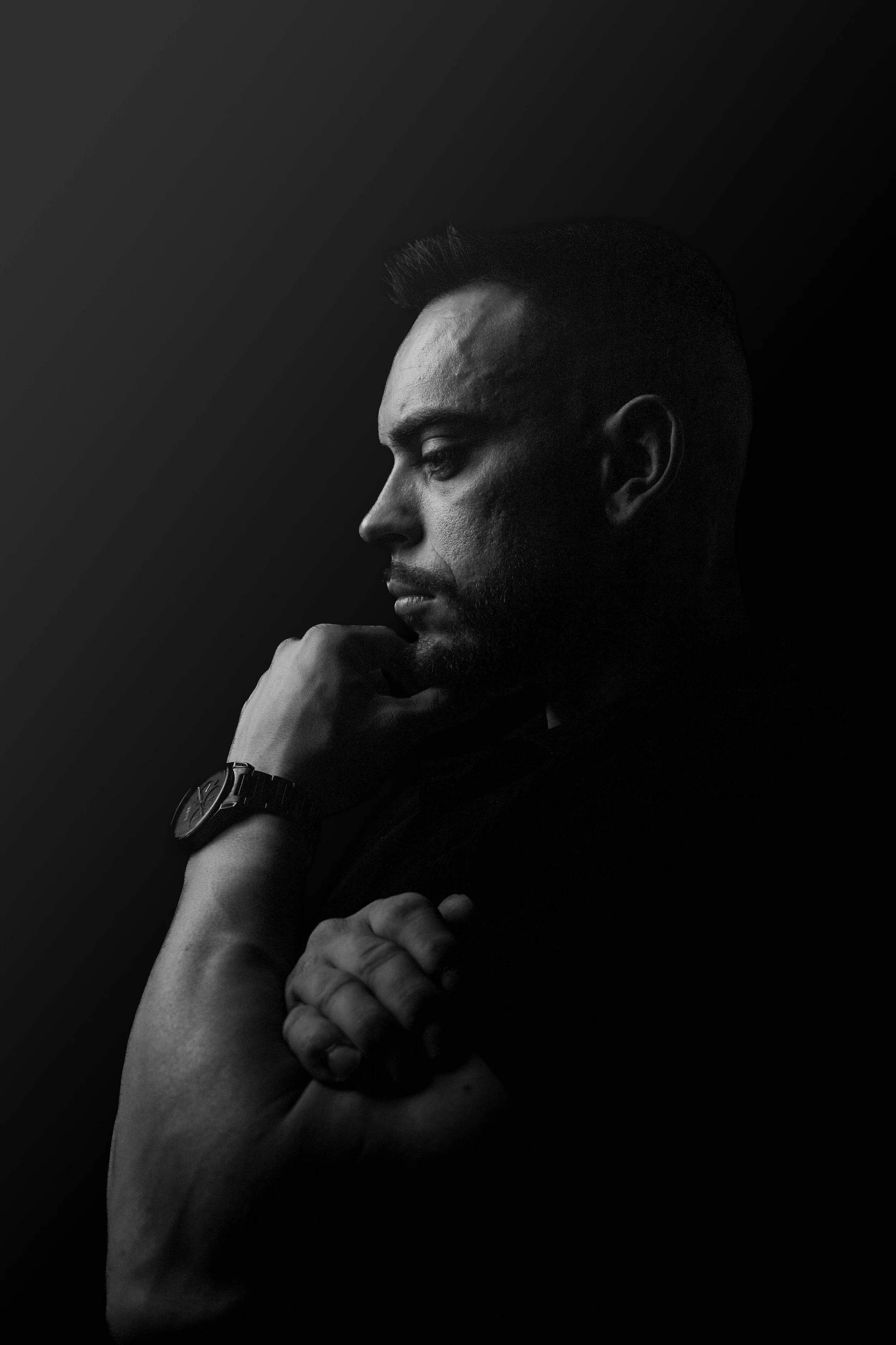 Retrato en clave baja con composición limpia y enfoque en la expresión del sujeto. La iluminación lateral crea una atmósfera emocional que potencia la profundidad y el contraste propio del blanco y negro. Una pieza visual elaborada cuidadosamente por