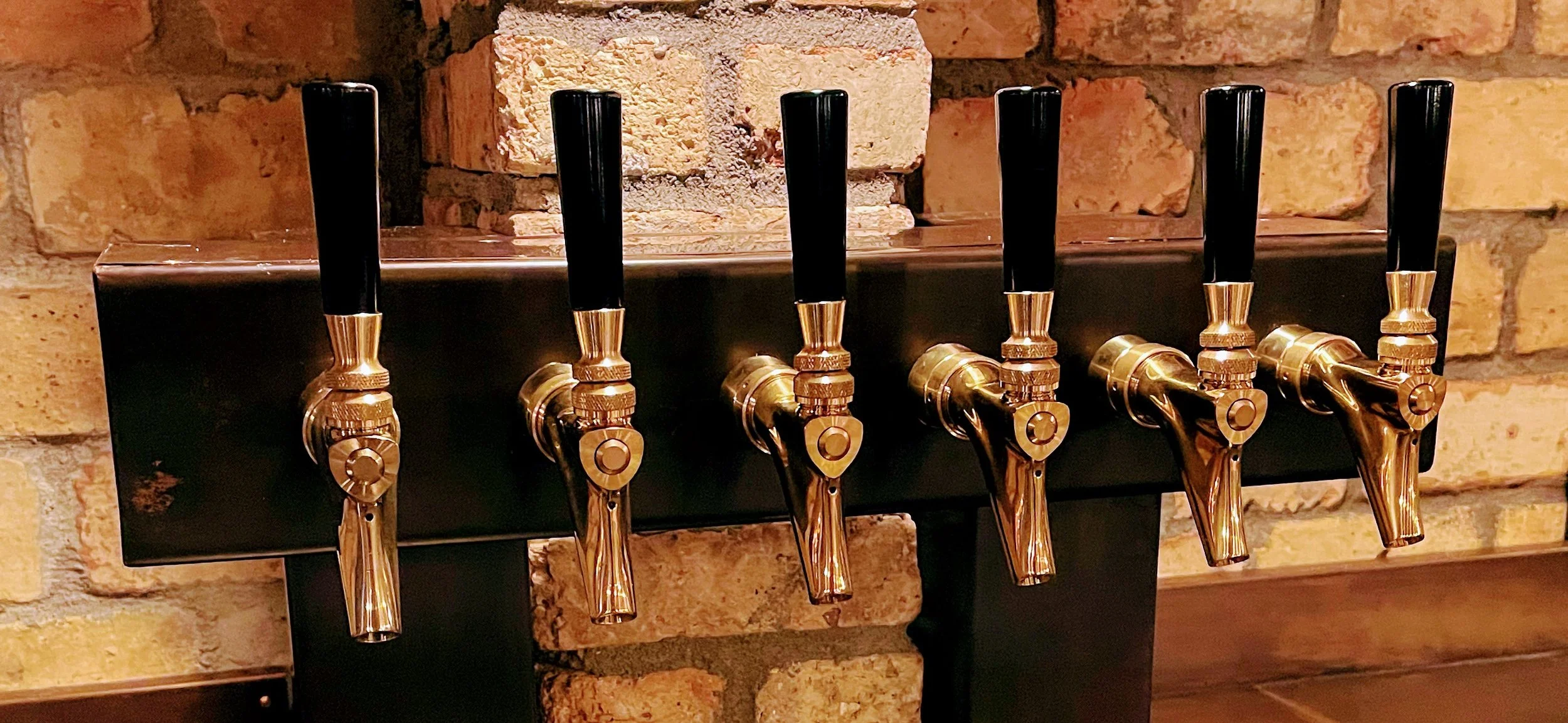 Completed custom copper draft beer tower with six polished Micro Matic 304 PVD brass faucets, professionally installed by Tapworks Northwest at a Northwest Washington bar