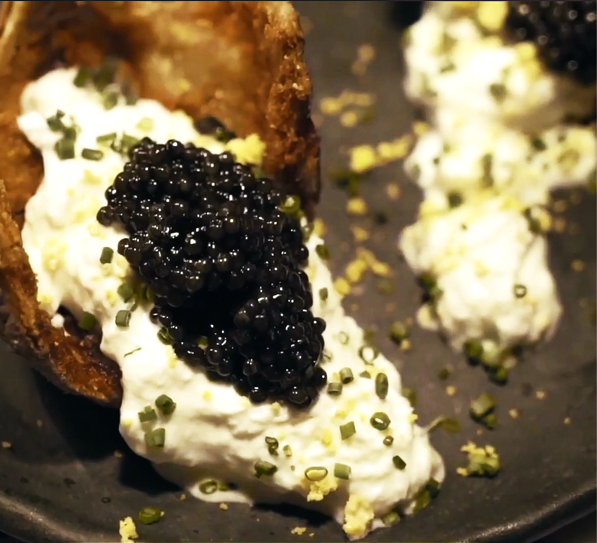 Tostada con crema, caviar negro y hierbas finas.