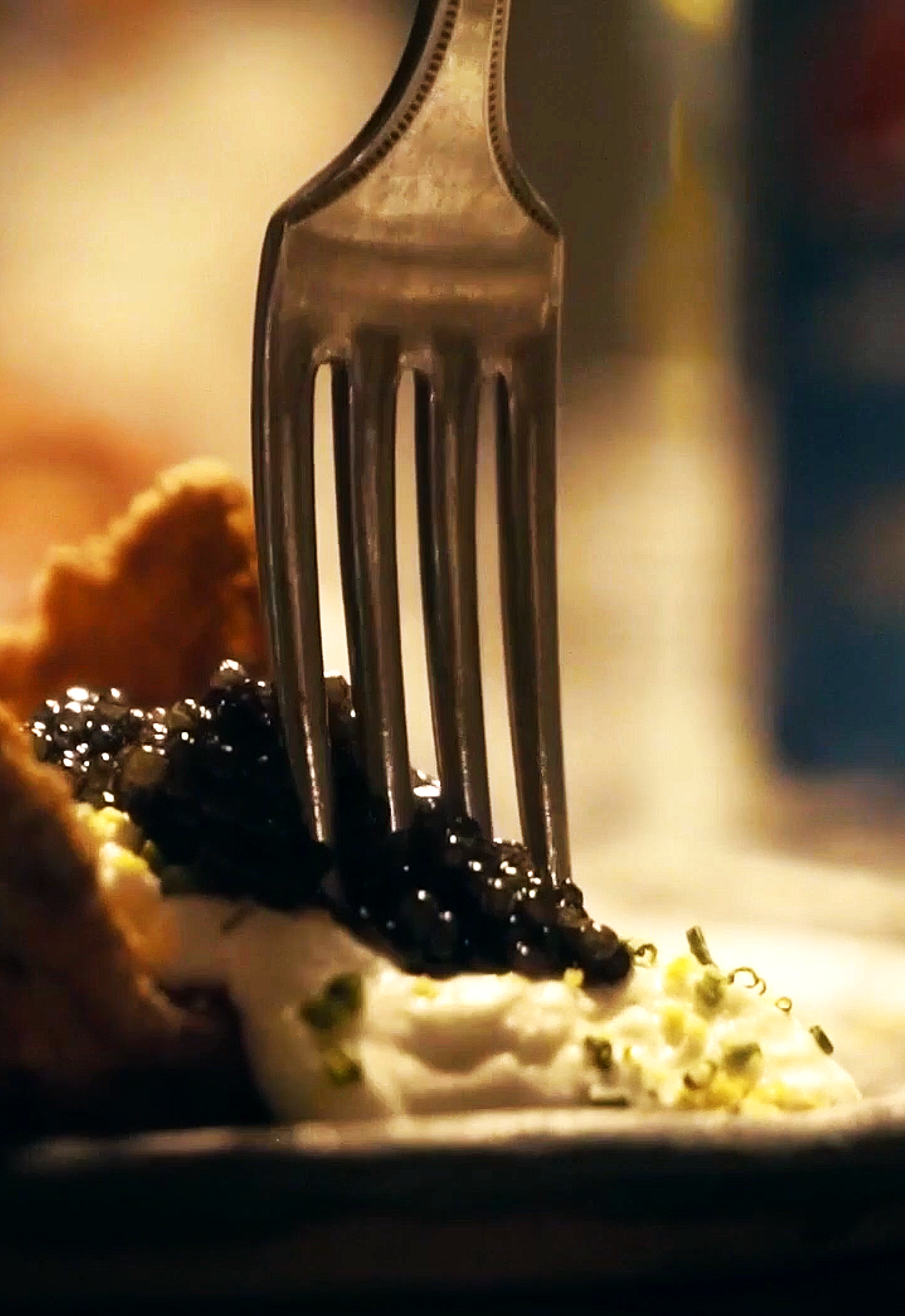 Un tenedor con salsa negra, crema y hierbas en un plato