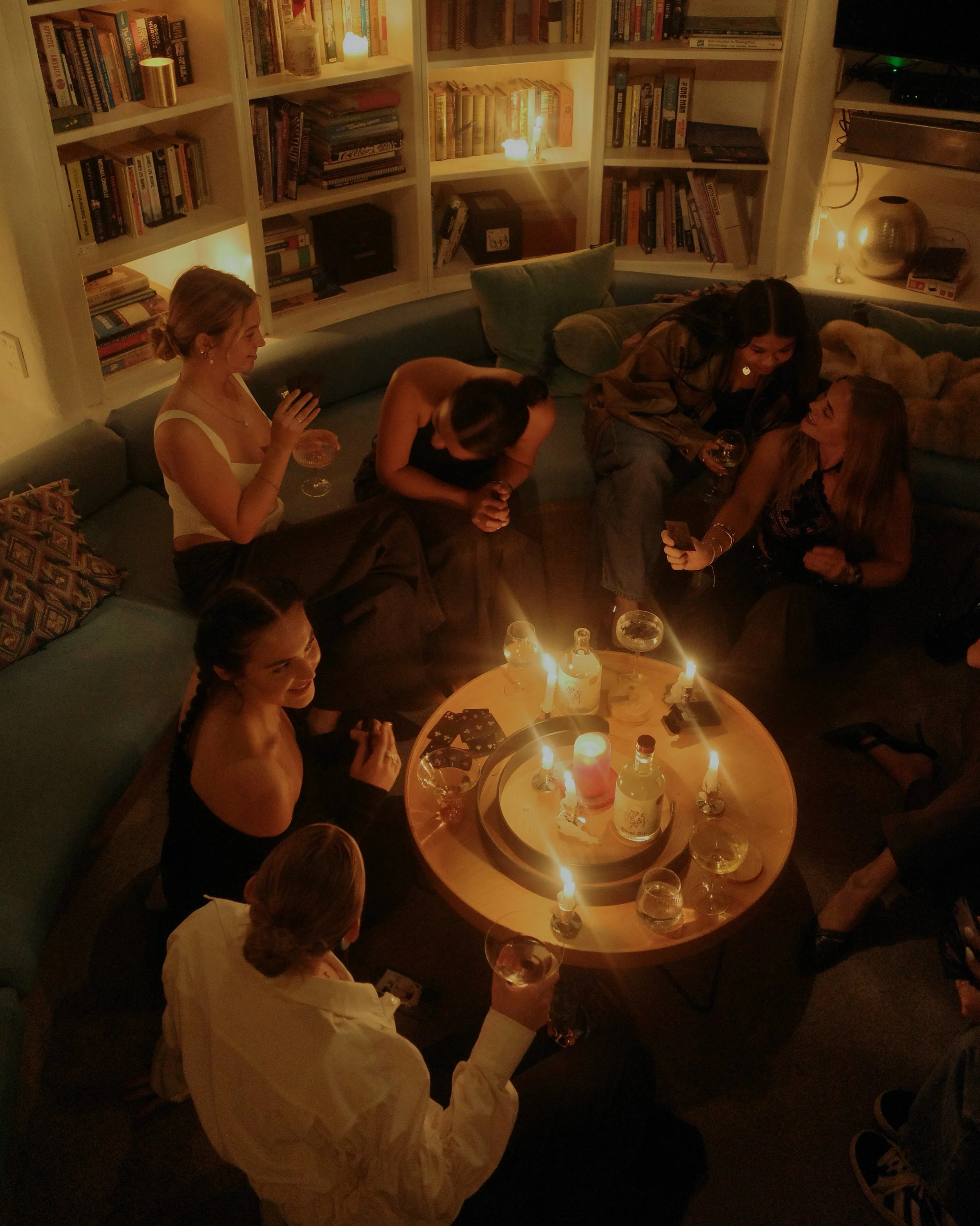Saint Sin Gin shared moment — friends gathered around candles and drinks, evoking connection and celebration.