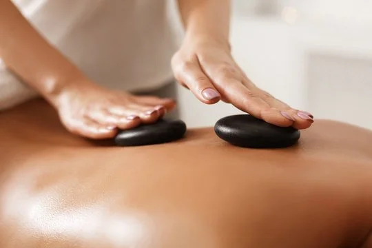 Close-up of a massage session with hot stones being placed on a person's back.