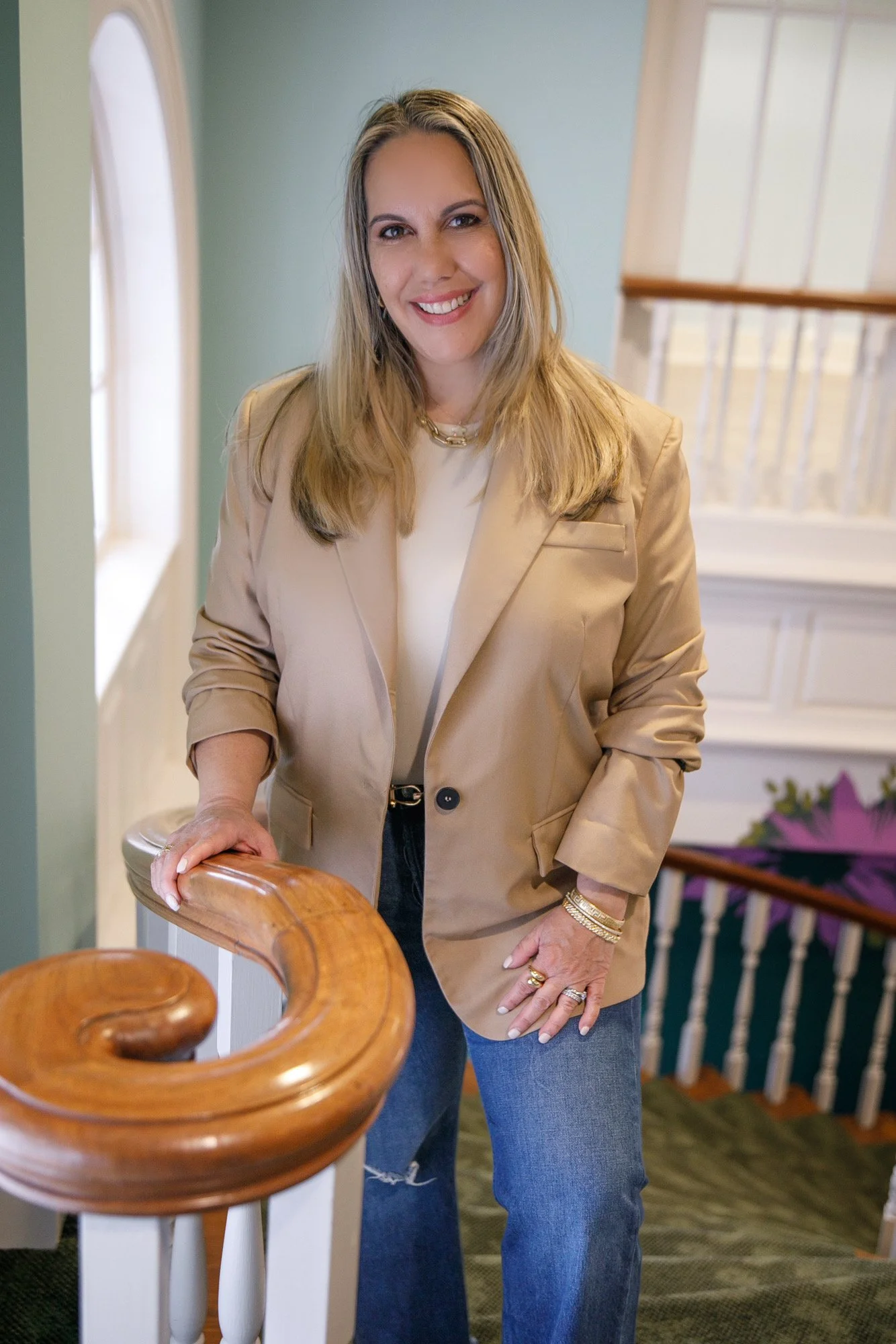 Katherine Beltran smiling on staircase — business coach helping entrepreneurs stop overthinking and start building momentum.
