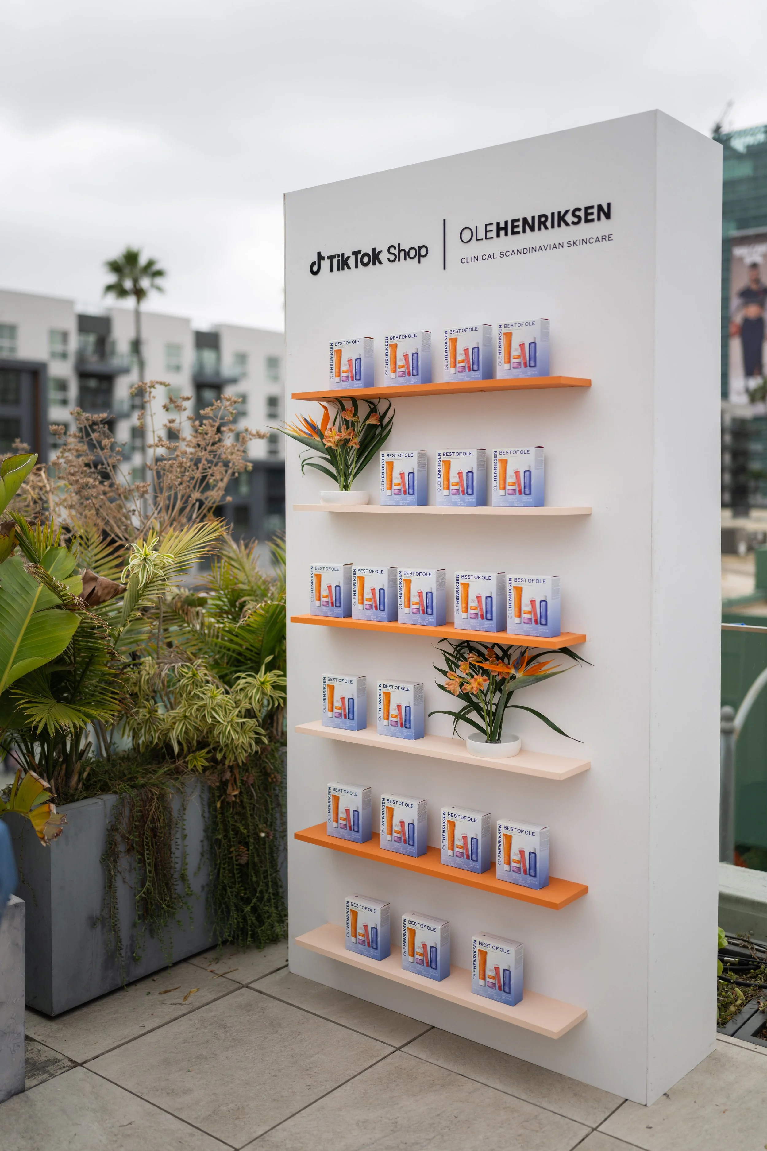 A display with skincare products and flowers at an outdoor retail setup, featuring branding for TikTok Shop and Ole Henriksen.