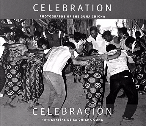 People dancing in a circle at a celebration, holding hands, outdoors with decorations and trees in the background, in black and white.