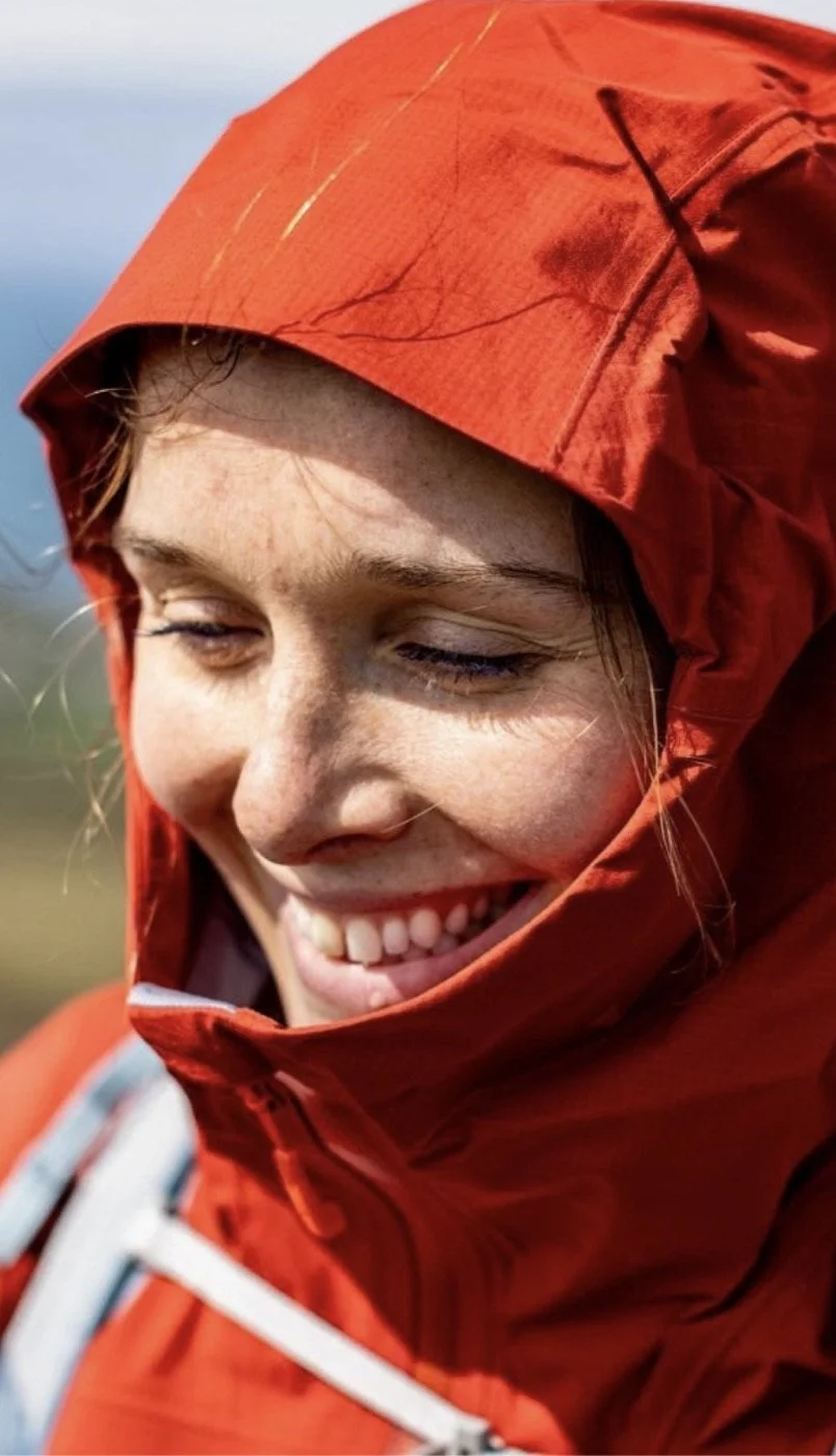 Emma smiling in a red waterproof hood