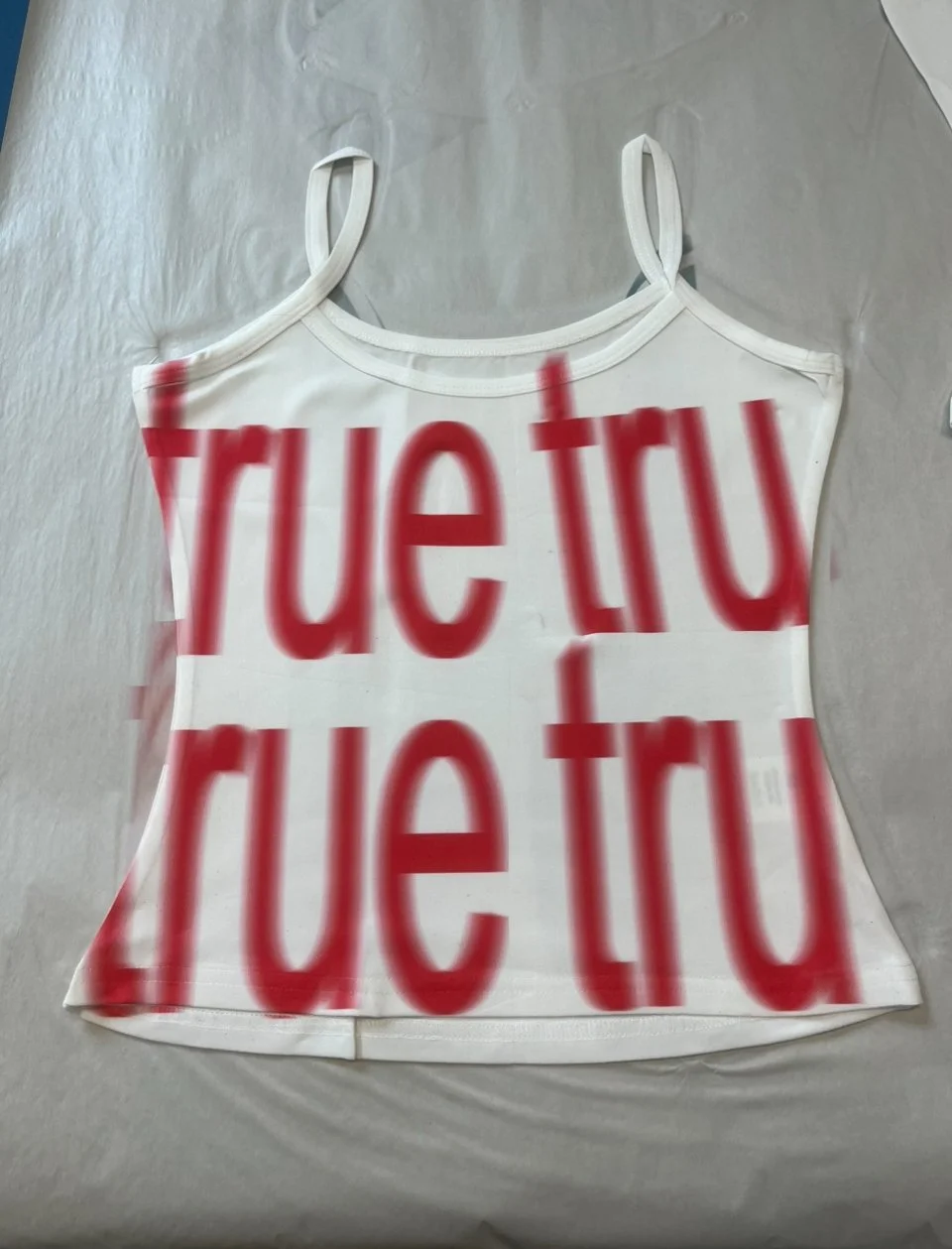 White mesh cami top with large red "true" text printed in repetition across the front.