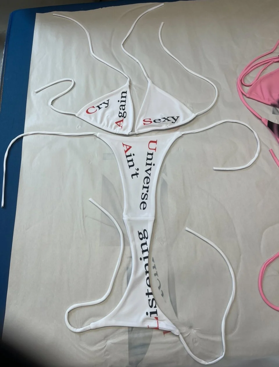 Glitchcore conceptual bikini printed with absurd poetic fragments in red and black text