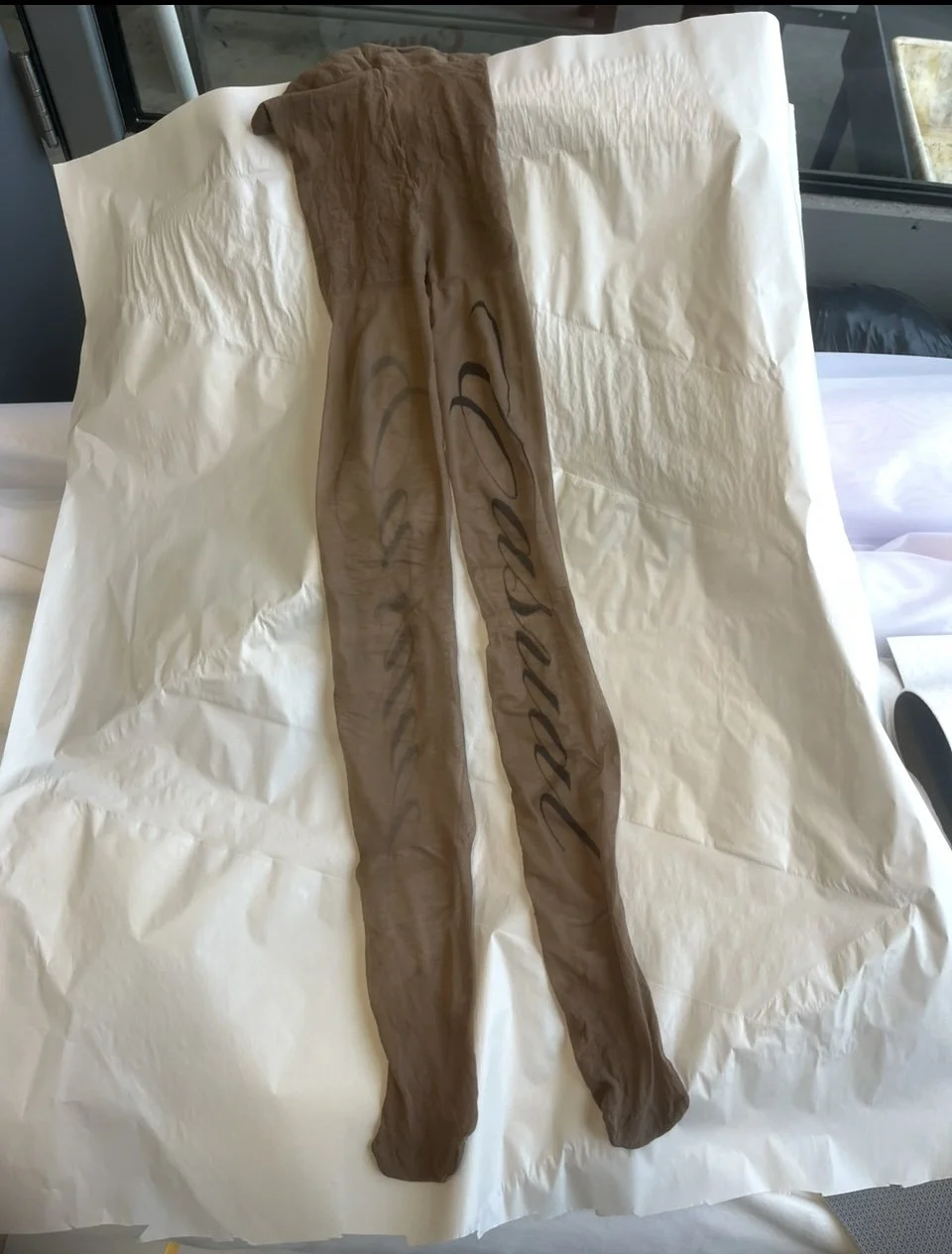 Darker brown tights laid flat, showcasing vertical script design.