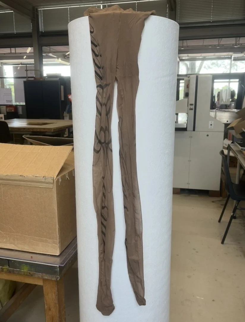 Brown variant of tights with same cursive lettering on right leg.