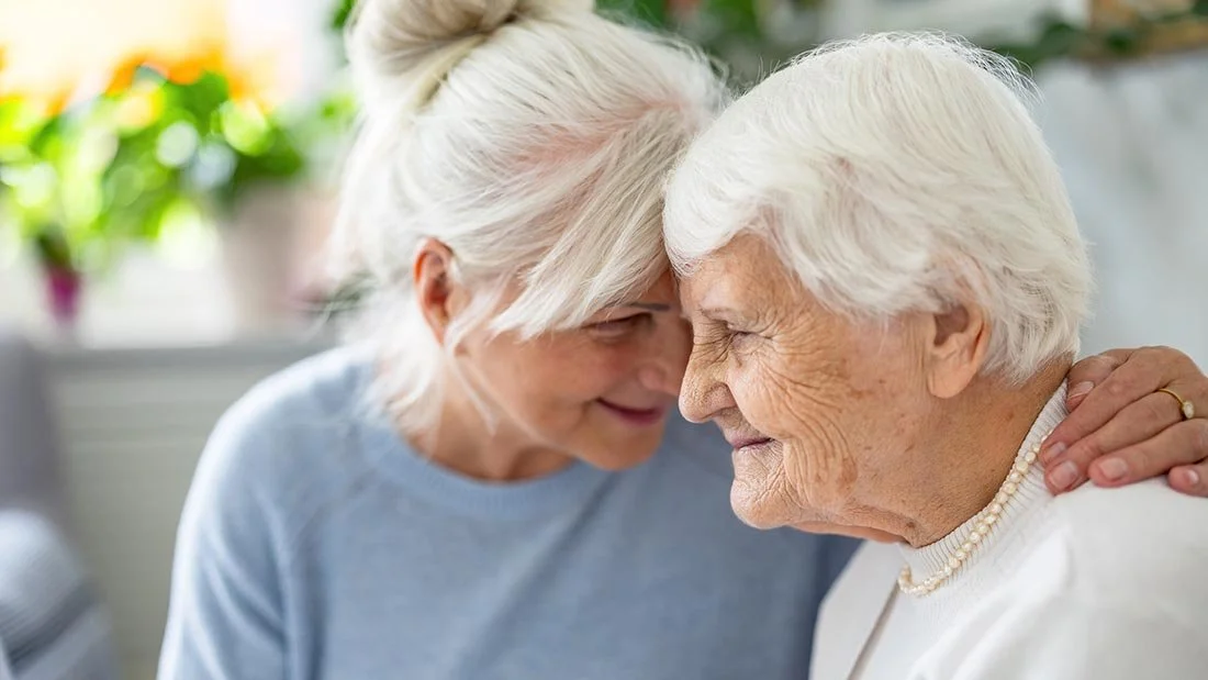 happy senior woman with her adult daughter at home