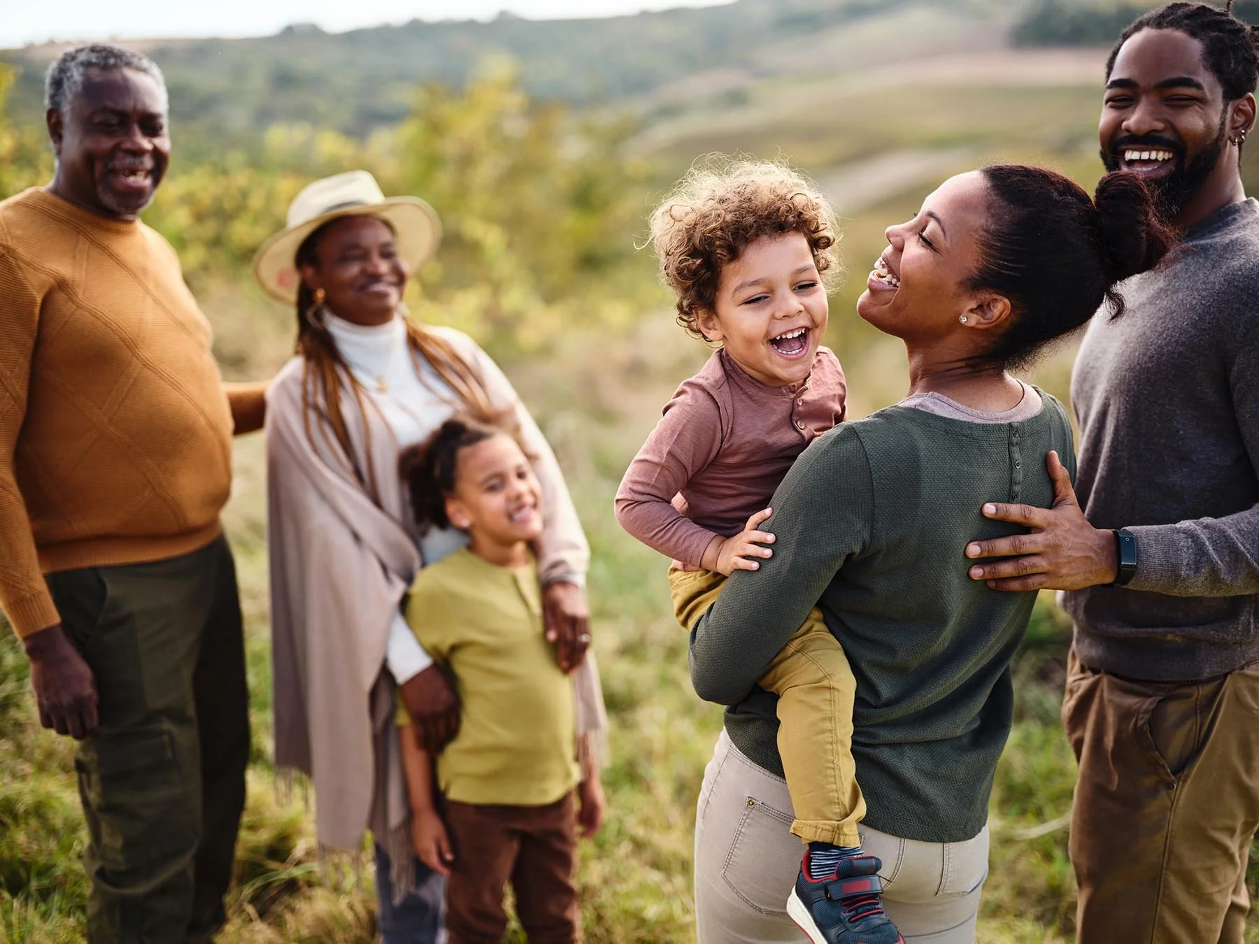 family of grandparents, parents, and kids enjoying an afternoon surrounded by green hills in soft light