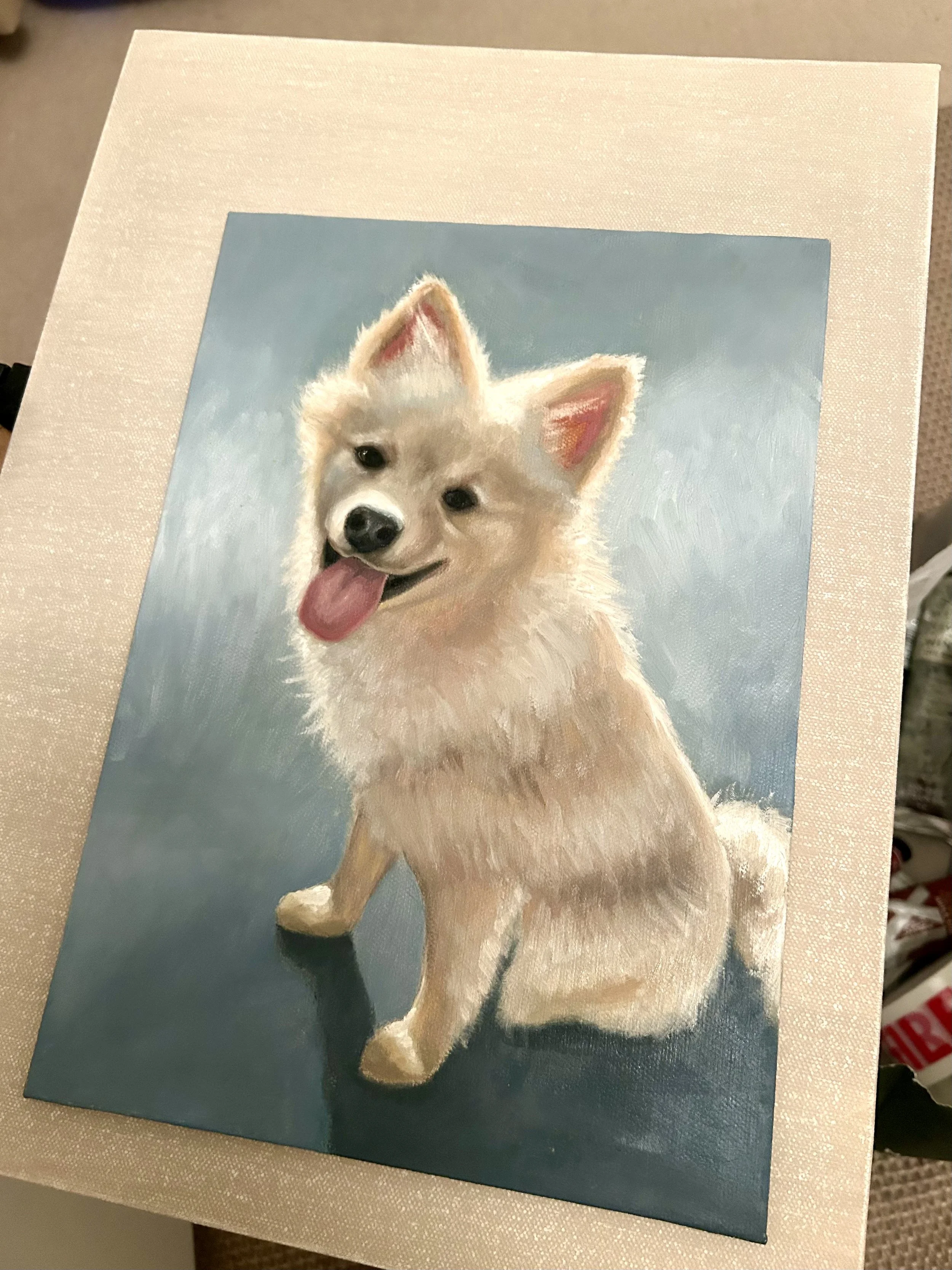 Painting of a happy, fluffy dog with light-colored fur, sitting with its tongue out, against a blue background.