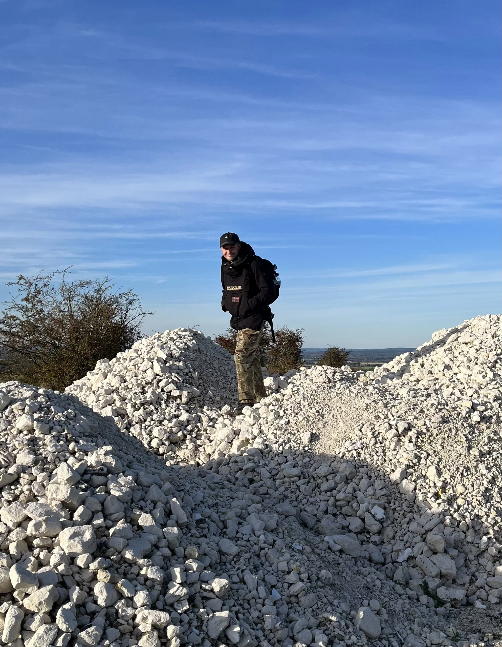 Person standing on piles of white chalk rocks with a clear blue sky.