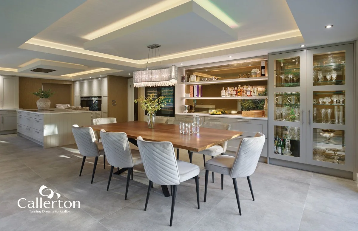 Modern dining room with a wooden table, eight upholstered chairs, glass-front cabinets, and a decorative light fixture in a well-lit space.