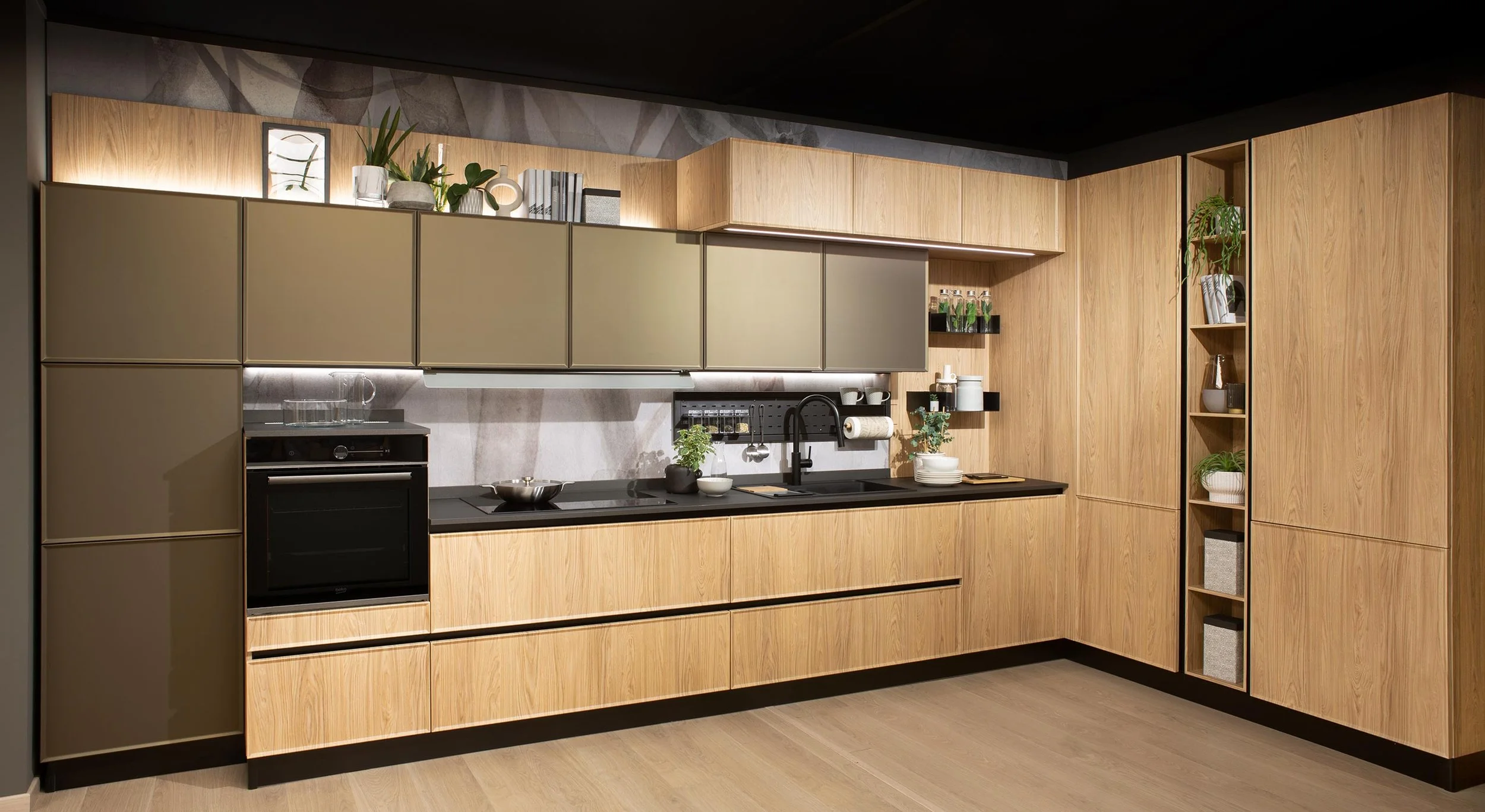 Modern kitchen with wooden cabinetry, black countertops, and open shelves with plants and decorative items.