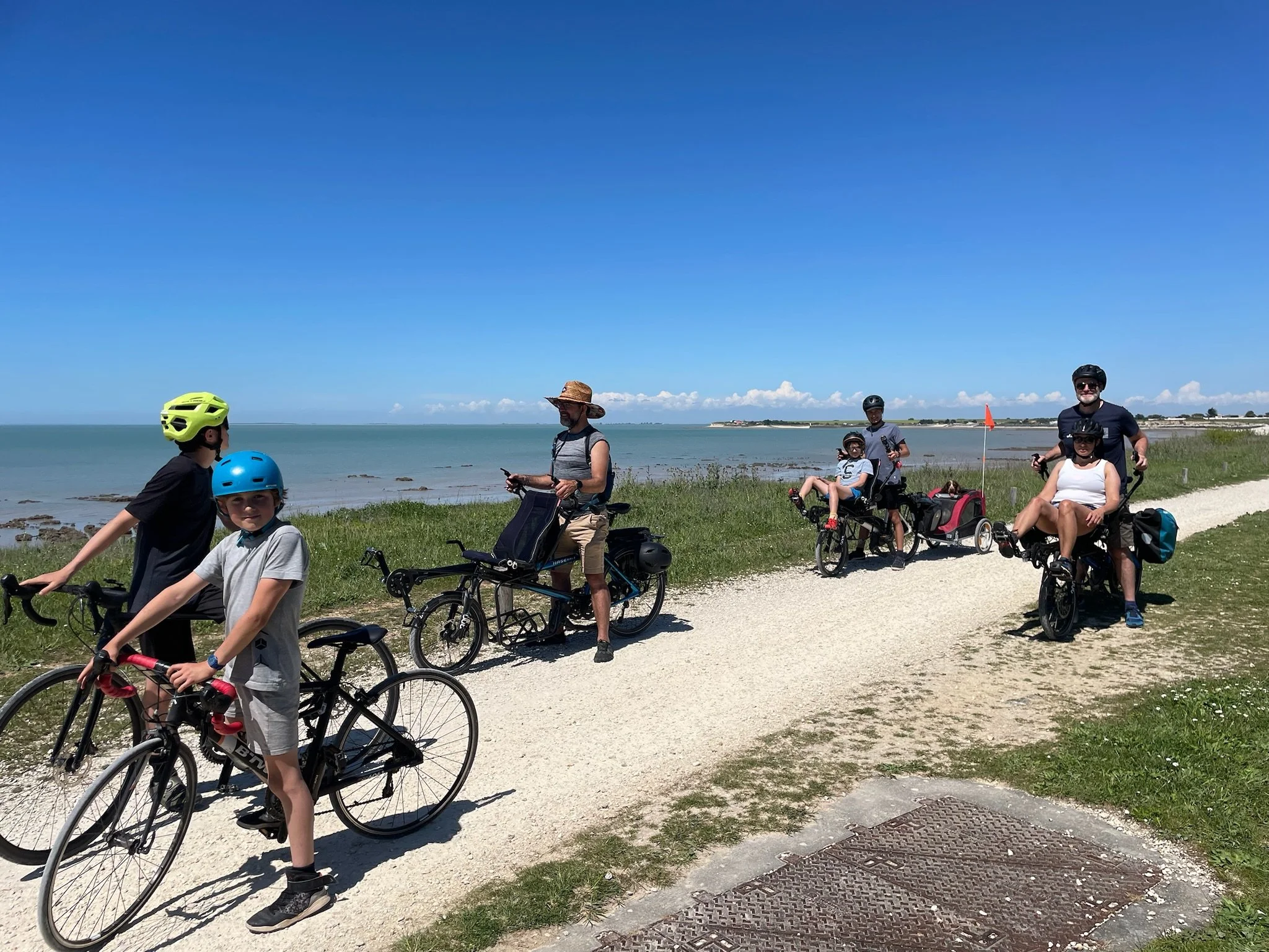 Group of people with bicycles and Tandem Pino by the sea on a sunny day.