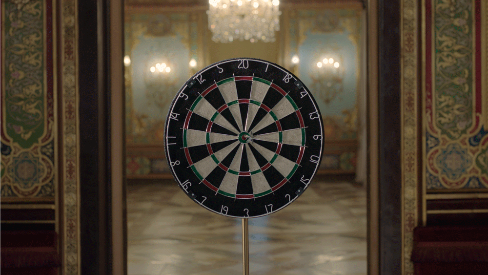Una diana de dardos en un lugar elegante con paredes decoradas y candelabros.