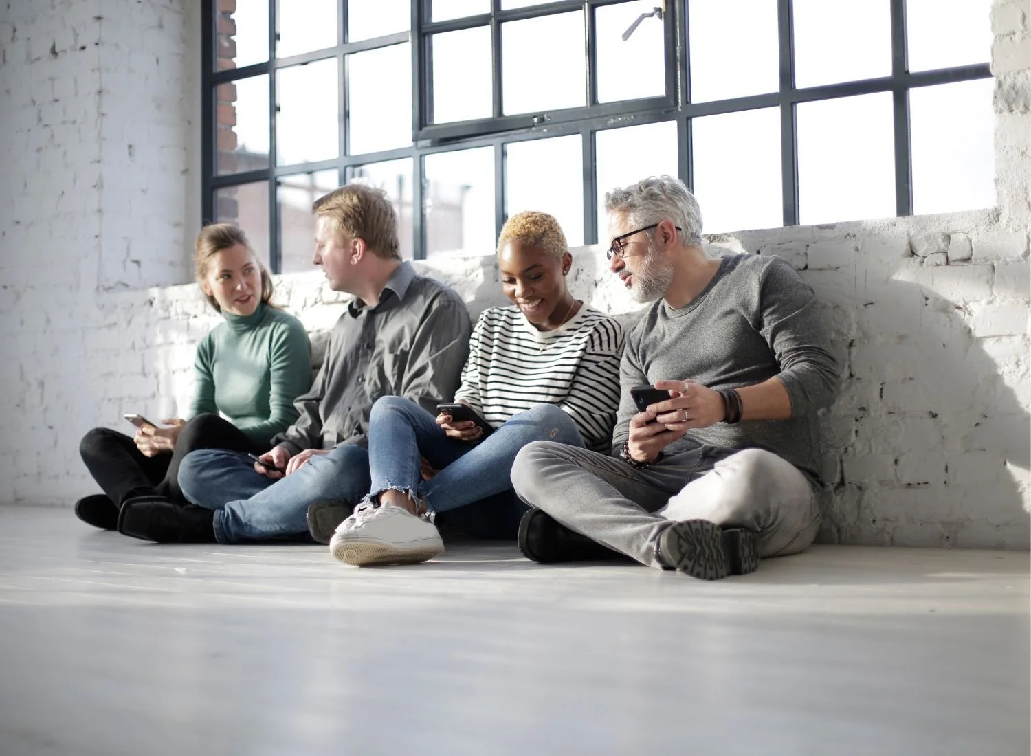 Four people sitting on the floor talking.