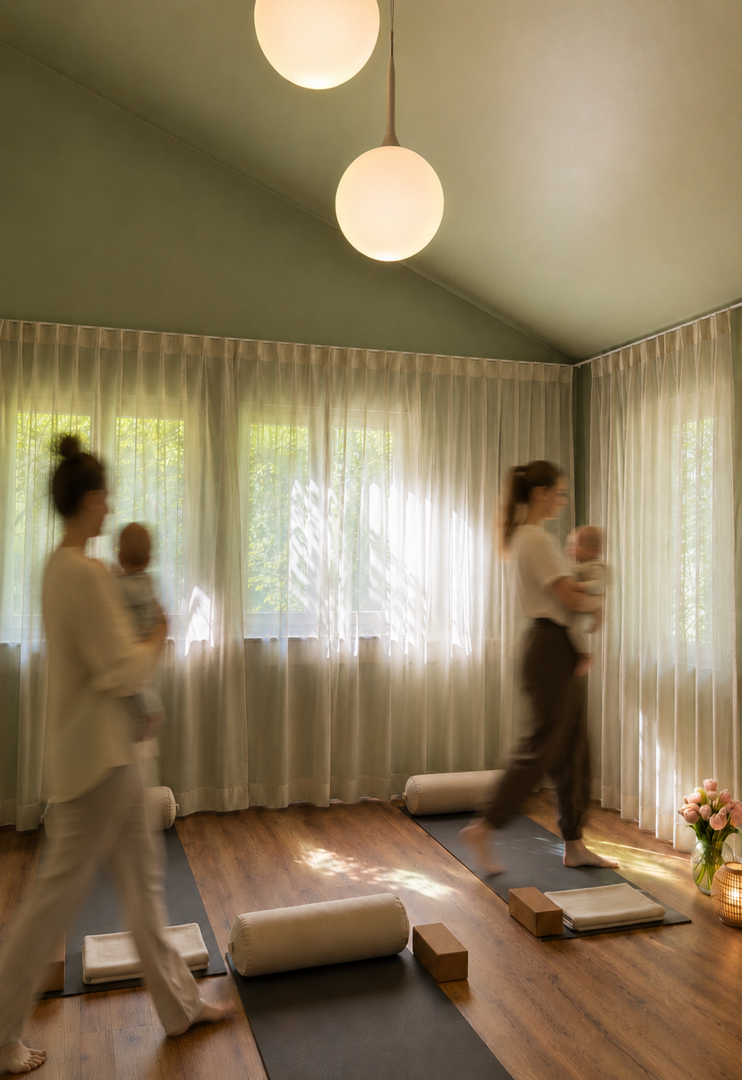 Zwei Frauen mit Babys, die in einem ruhigen Raum im Yoga oder Entspannungsunterricht Yoga-Übungen auf Yogamatten machen, mit Vorhängen vor den Fenstern und Pflanzen im Raum.