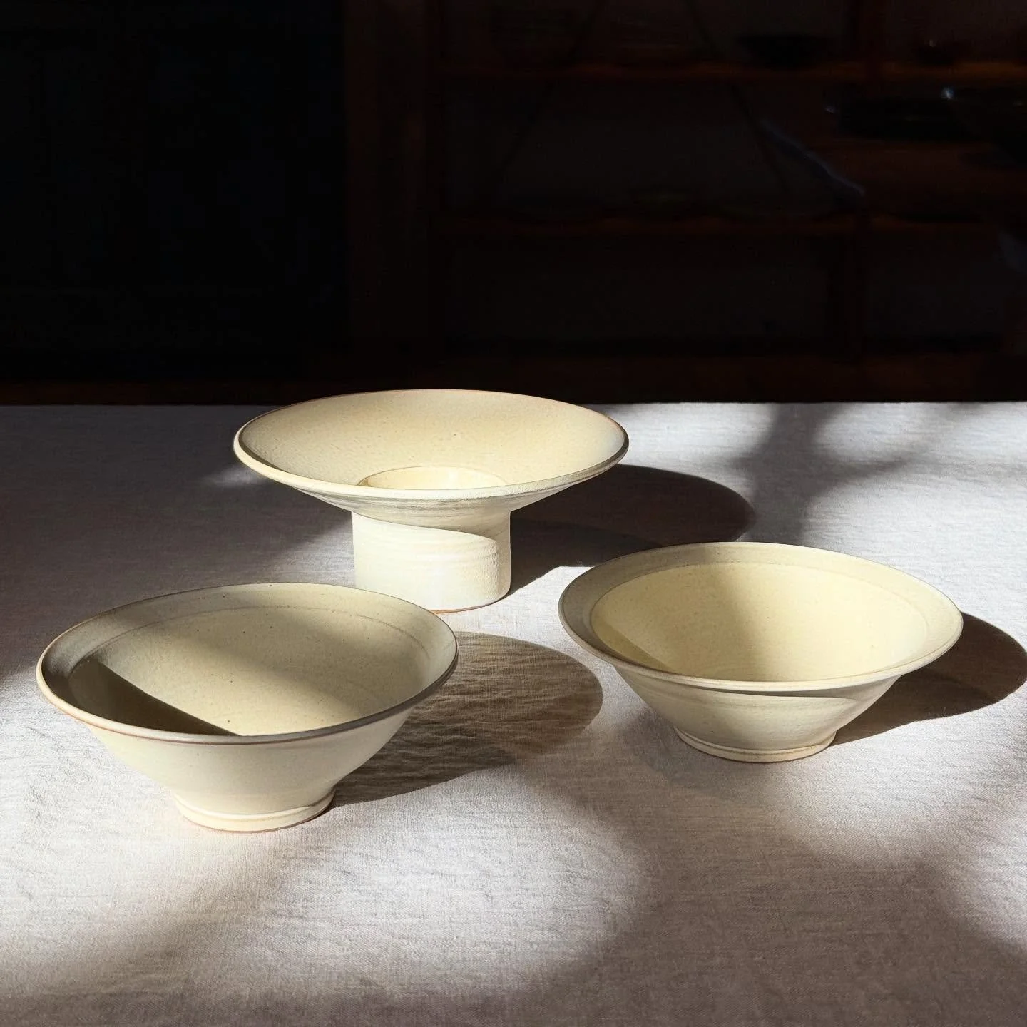 Skålar med krämvit halvmatt glasyr i höstsolen som strilar in.
#keramik #stengods #skålar #drejat #konsthantverk 
#ceramics #stoneware #bowl