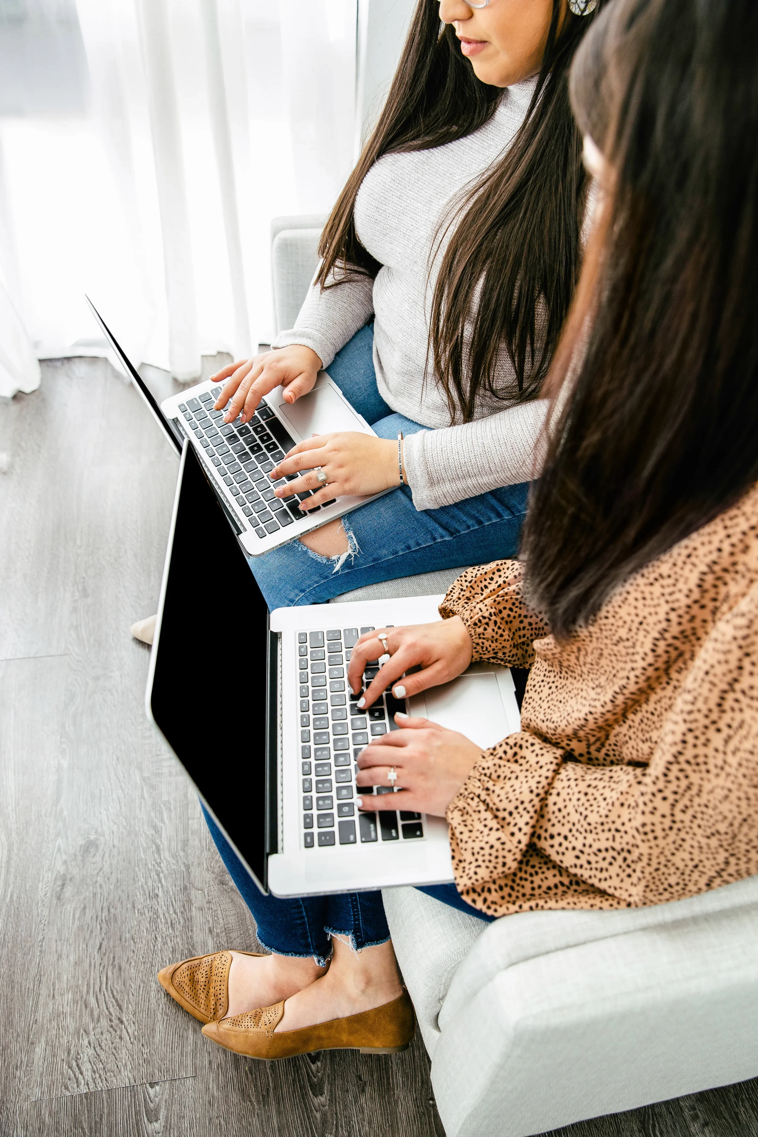 Two women working together each on a laptop