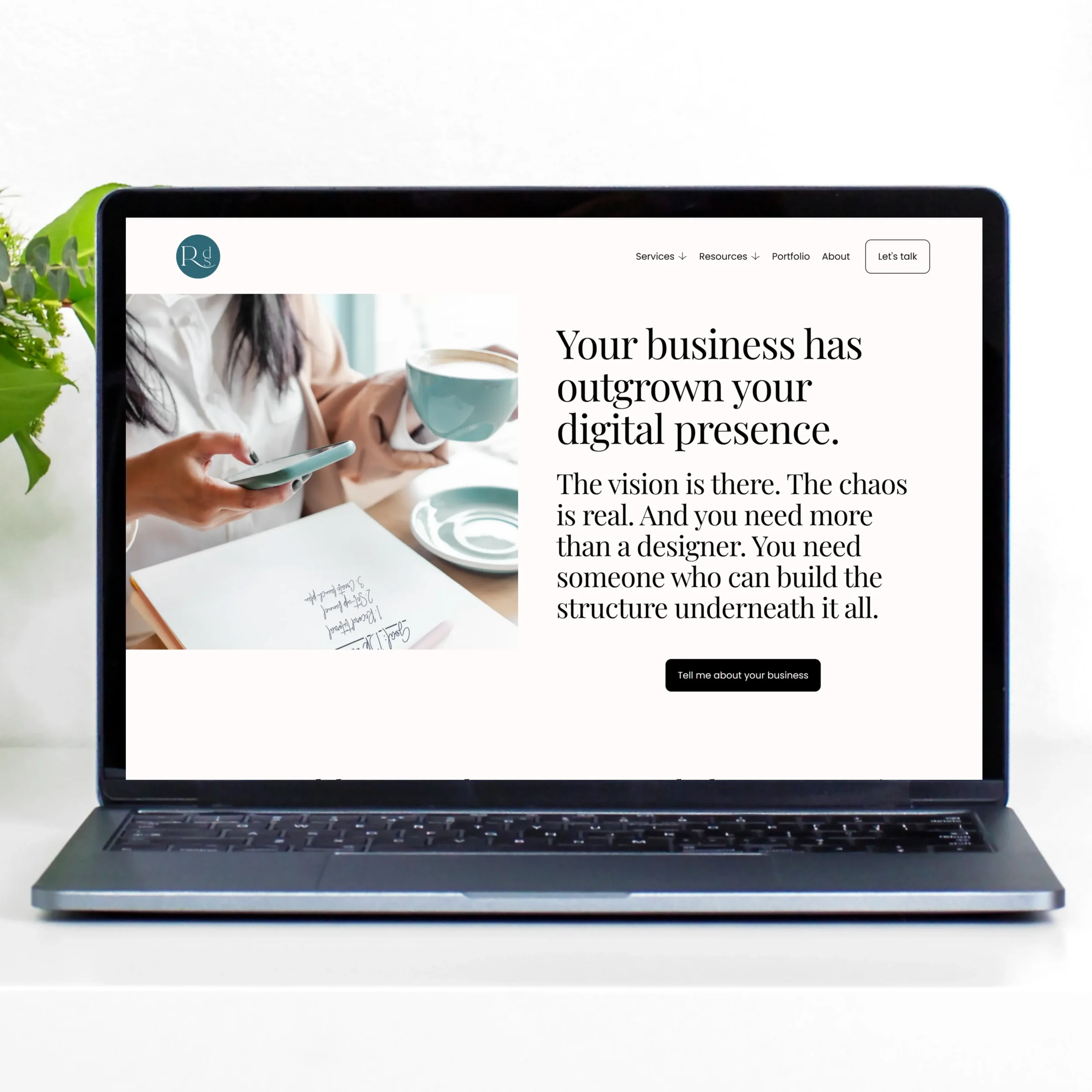 Laptop screen with Refresh Design Studios' homepage on a neutral background with greenery in the top left corner