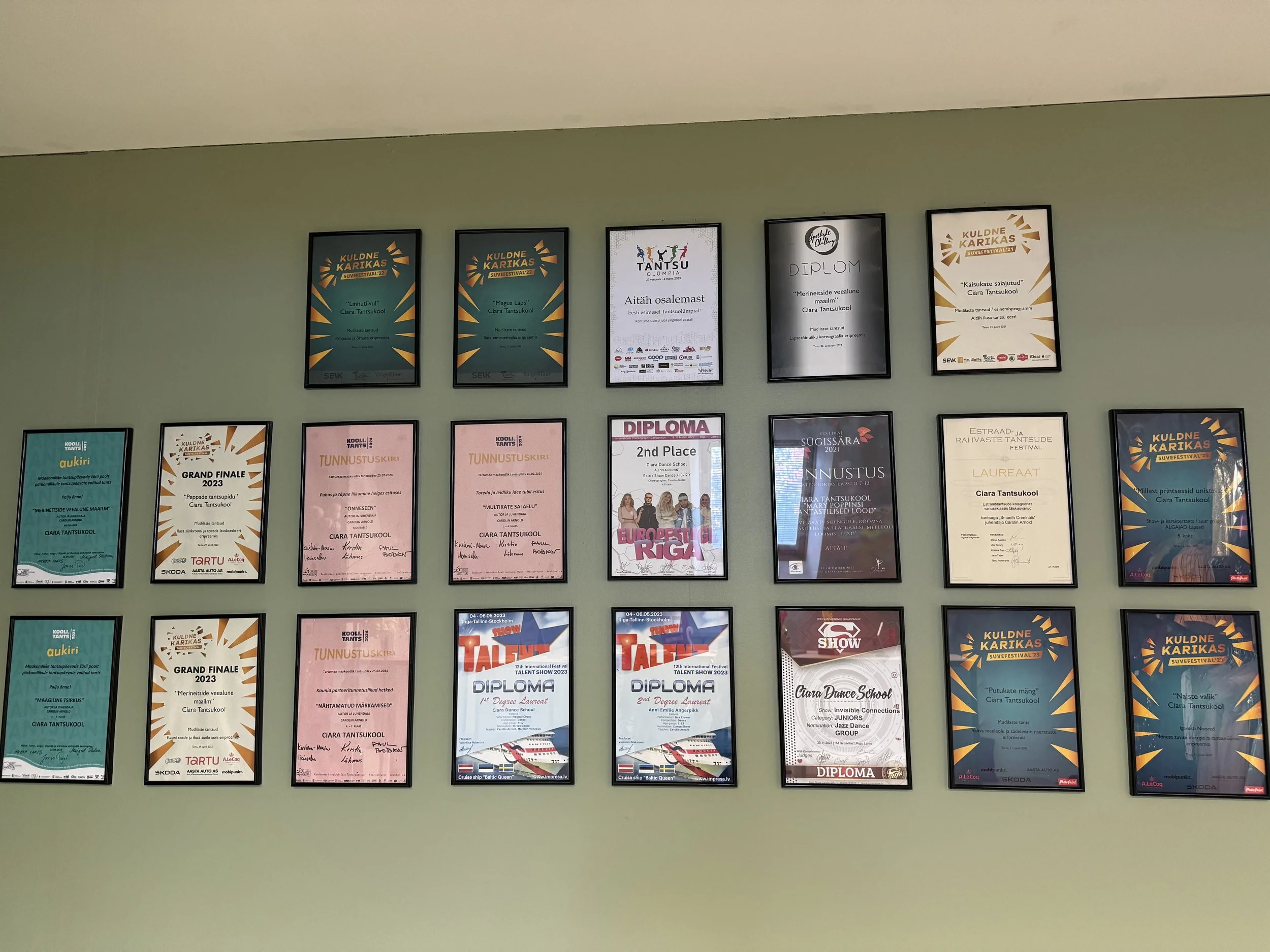 A wall displaying multiple framed awards, certificates, and diplomas arranged in a grid, with some certificates featuring colorful and branded designs.