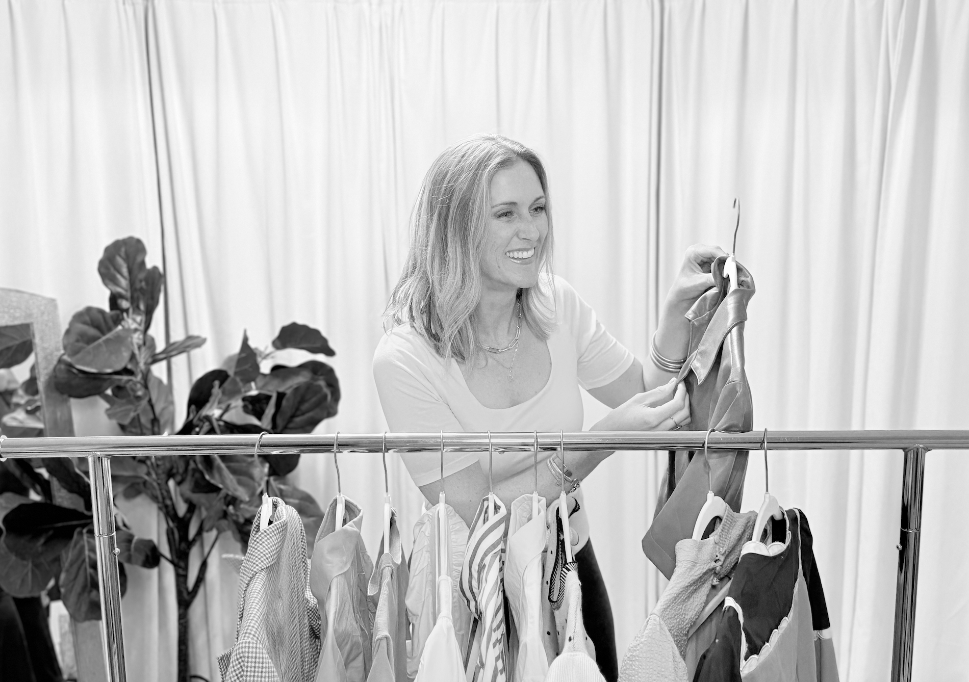 personal stylist holding a garment to a client with a clothing rack and happy; wardrobe stylist; dallas fort worth fashion stylist